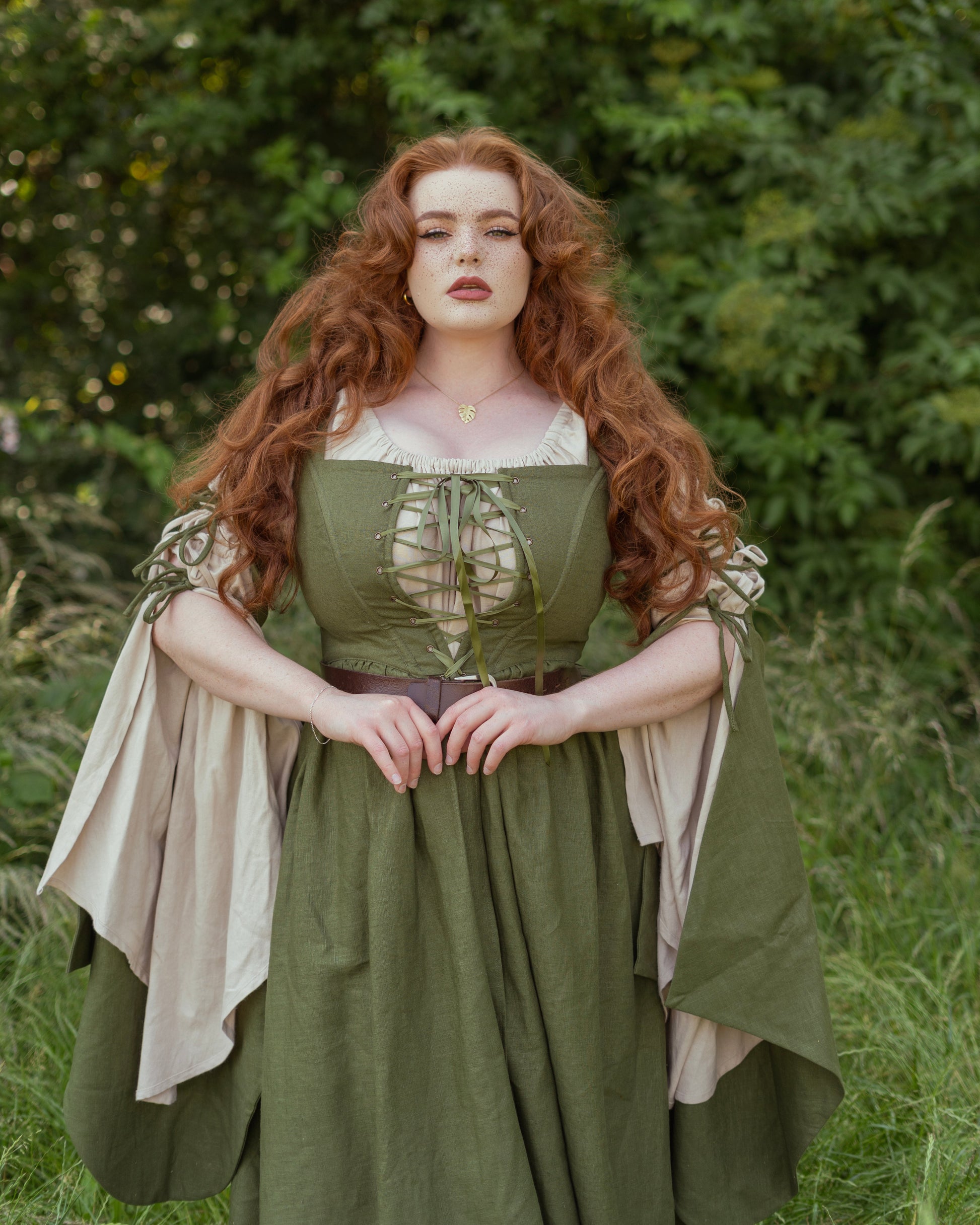 Woman in a green dress with a beige chemise standing in a natural setting