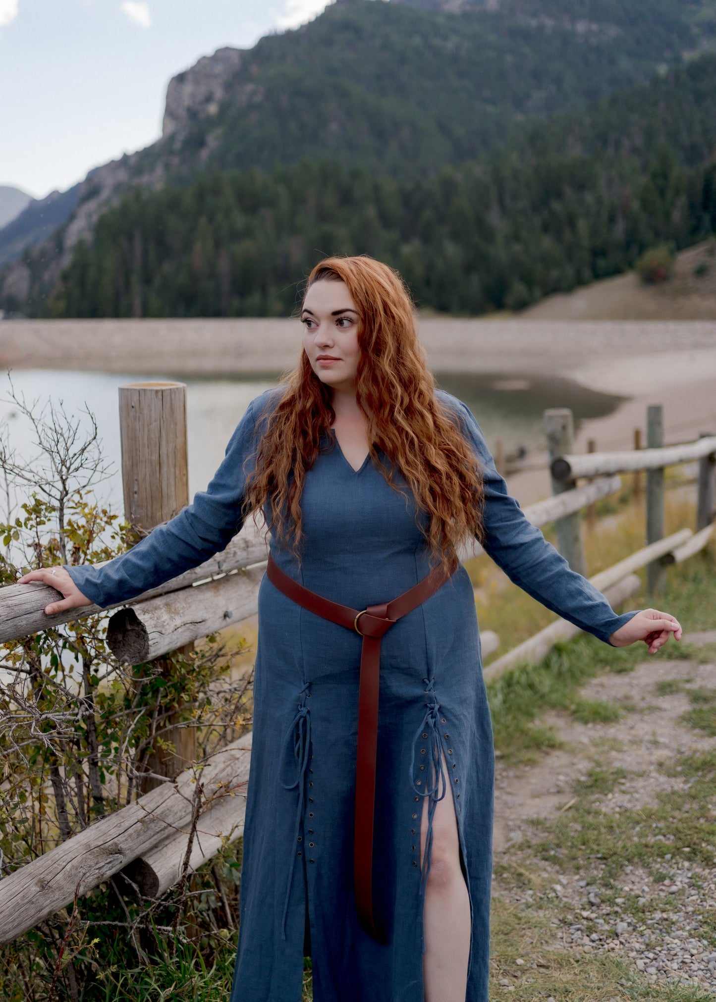 Teal Viking Dress shown in outdoor mountain setting with laced front panels and fitted bodice, styled with brown leather belt