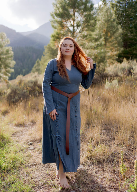 Teal Viking Dress shown outdoors in mountain setting, featuring fitted silhouette, laced front detail and leather belt against nature backdrop