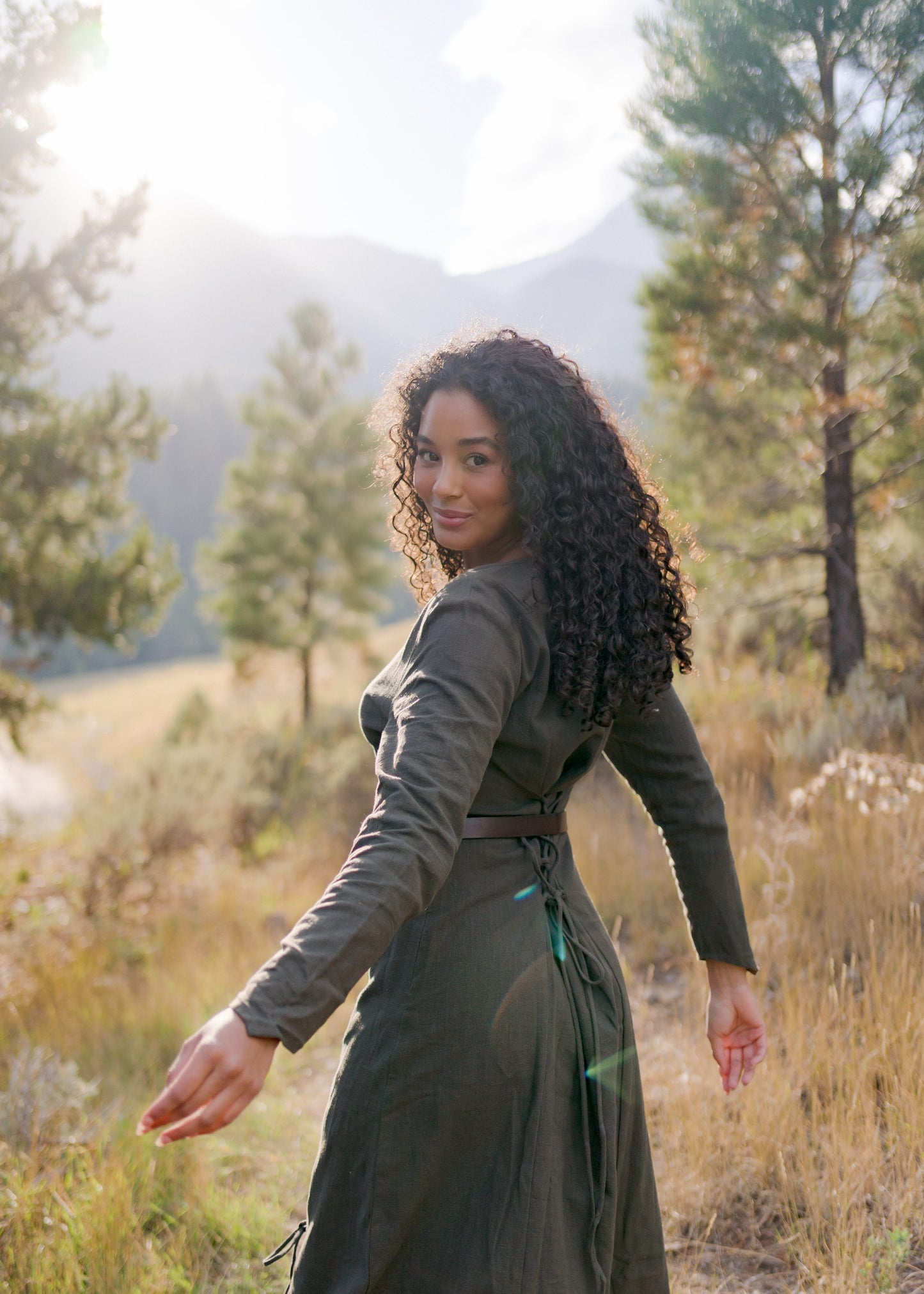 Olive Green Viking Dress shown in outdoor mountain setting, featuring laced back, fitted silhouette and long pointed sleeves