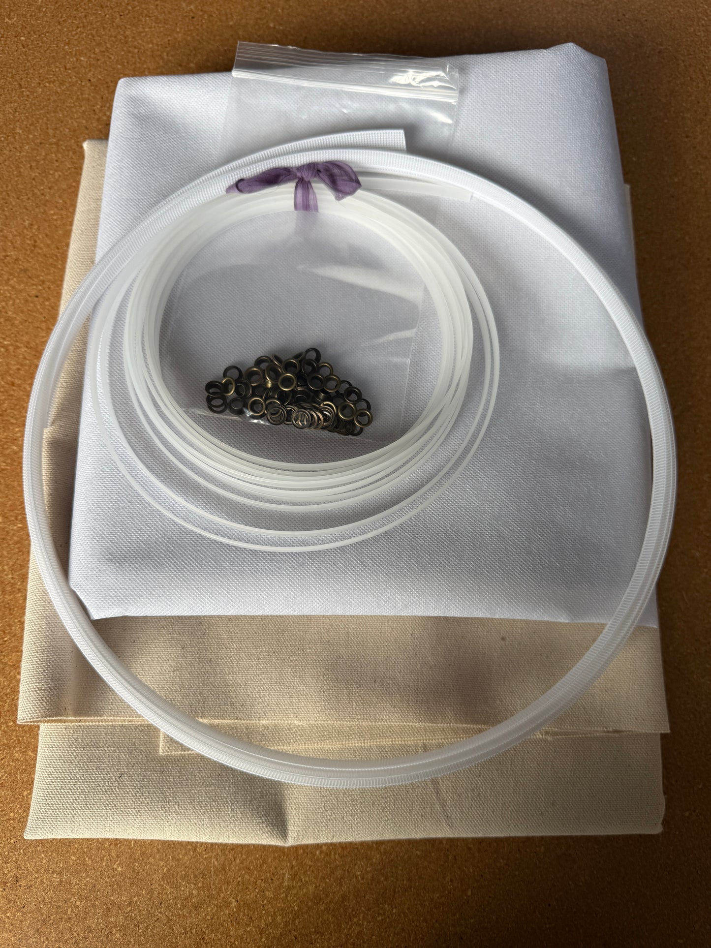 Corset Making Materials Kit with cotton canvas, fusible interfacing, plastic boning, rigiline, and bronze grommets on fabric sheets.