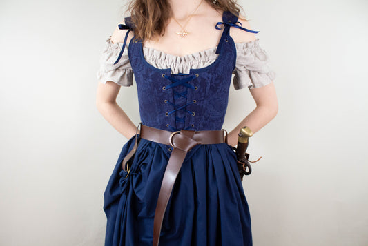 Woman wearing a Handmade Navy Blue Embroidered Floral Corset with a beige blouse and blue skirt tied with a brown belt
