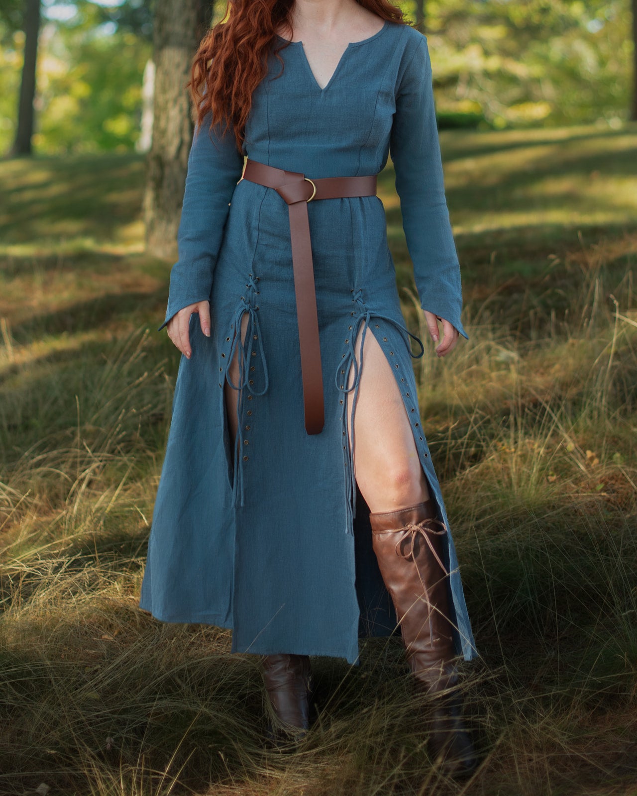 Teal Viking dress with laced front slits, fitted bodice, pointed sleeves and leather belt worn outdoors in natural setting