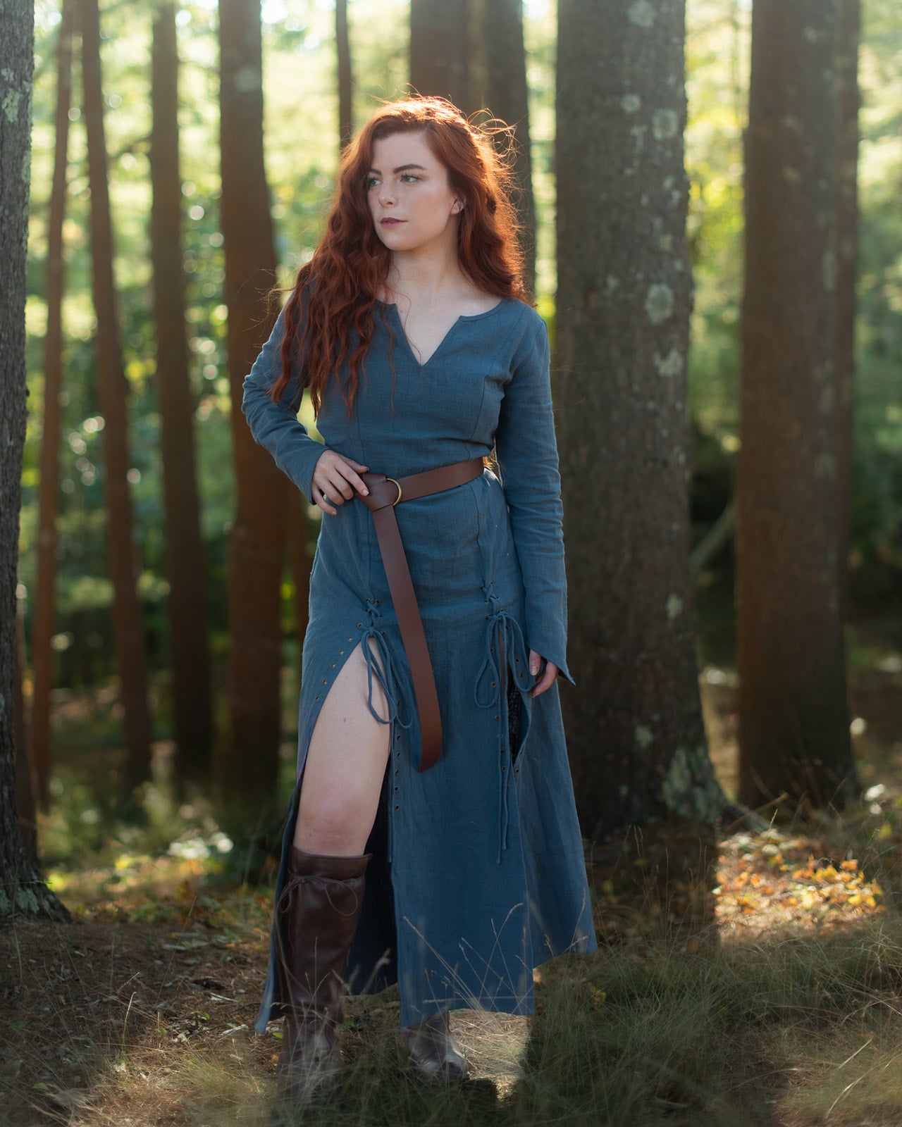 Teal Viking Dress with lace-up details shown in forest setting, featuring long sleeves and fitted silhouette with leather belt
