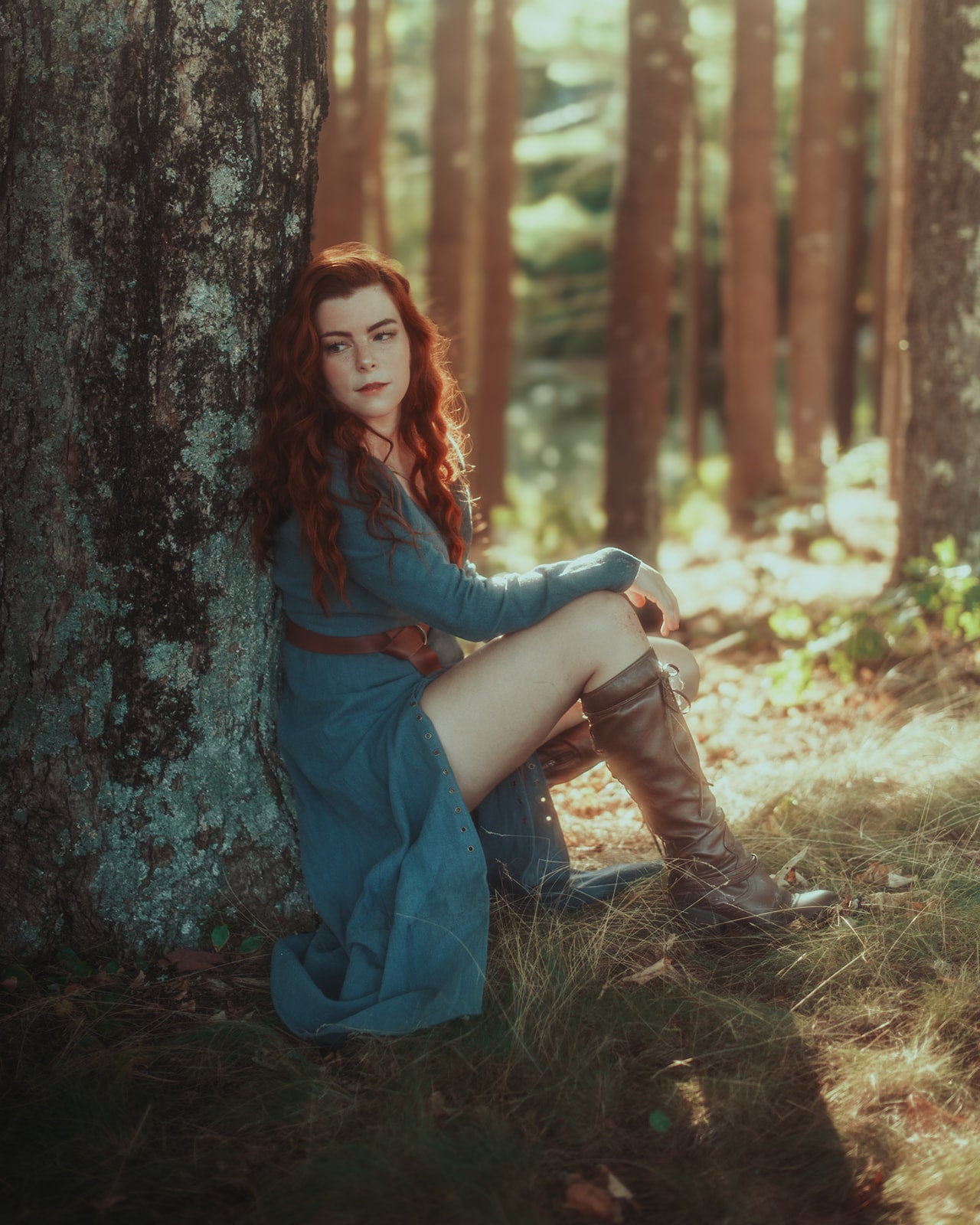 Teal Viking dress with pointed sleeves and front lacing shown in enchanted forest setting with brown leather boots
