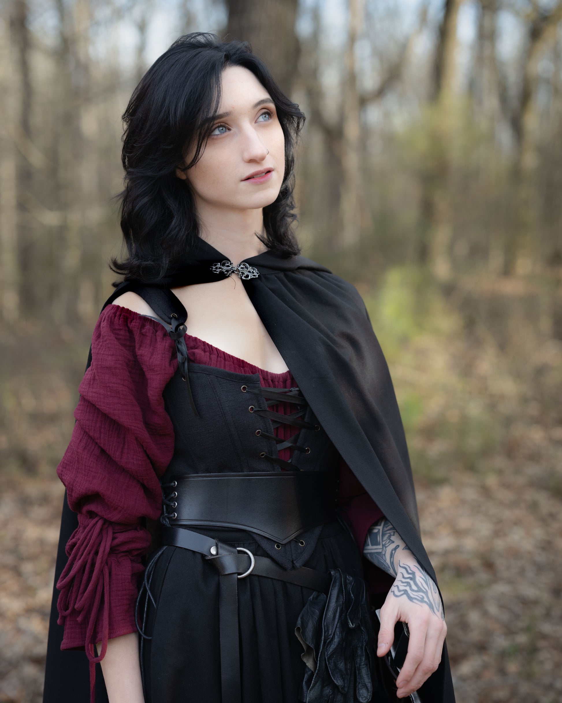 Black Cotton Corset Top styled with burgundy blouse and black cape in forest setting, showcasing gothic medieval fashion design