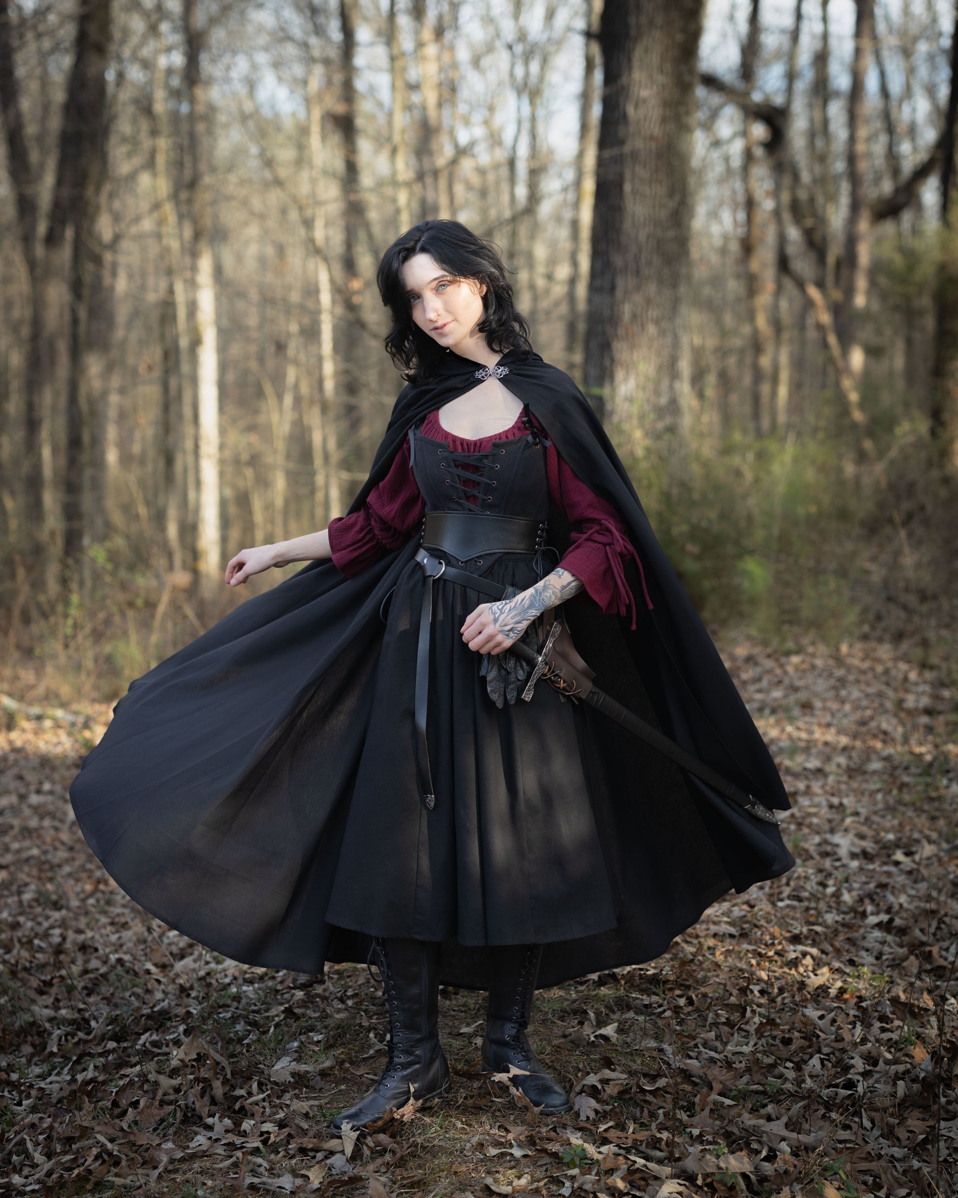 Black Cotton Midi Skirt twirling in forest setting, paired with burgundy blouse and dramatic black cape, renaissance-inspired styling