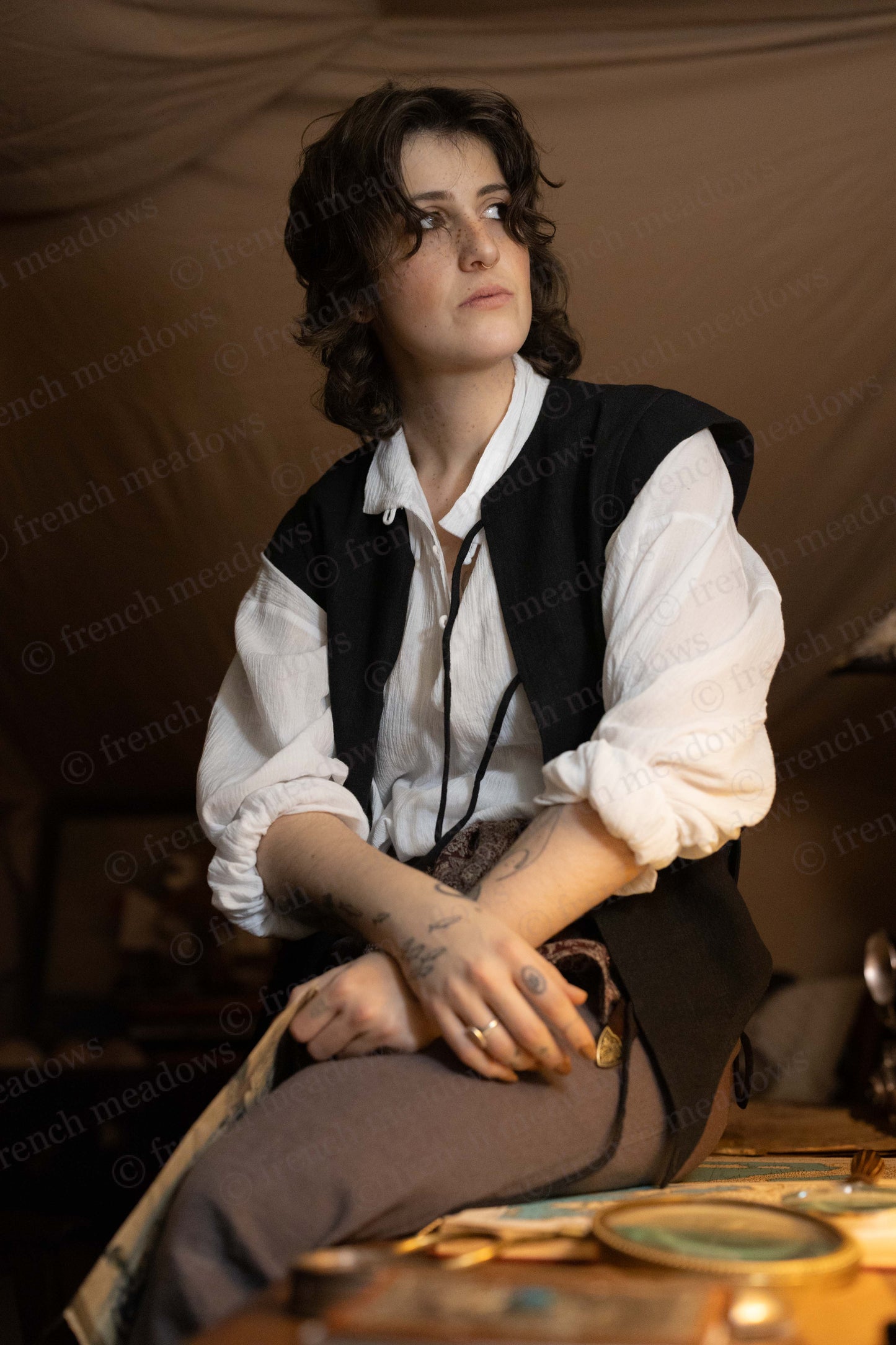 Black Bard Vest shown with white renaissance shirt, styled in vintage theatrical setting against warm brown backdrop