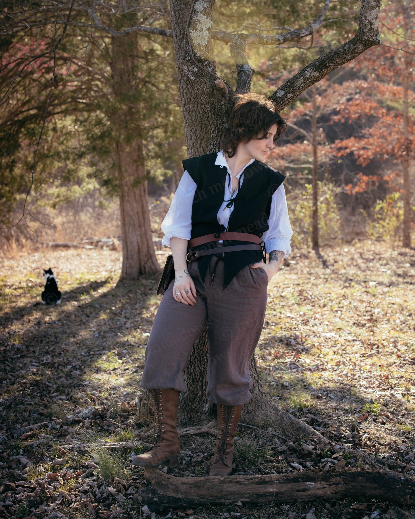 Black Bard Vest shown in woodland setting with brown pants, white shirt, and leather boots, styled in renaissance fashion