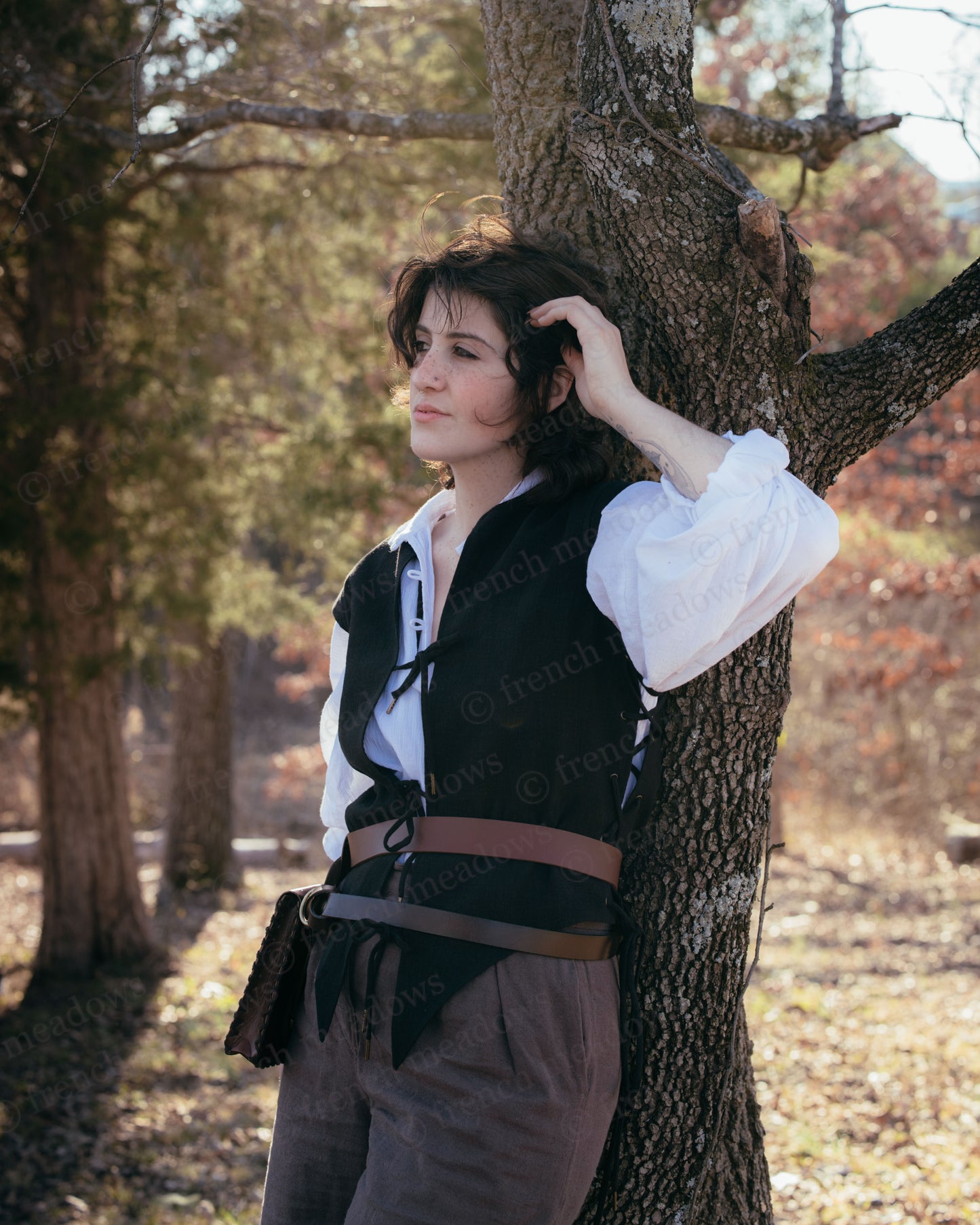 Black Bard Vest shown in woodland setting with white renaissance shirt and leather belt, displaying front tie details and fit