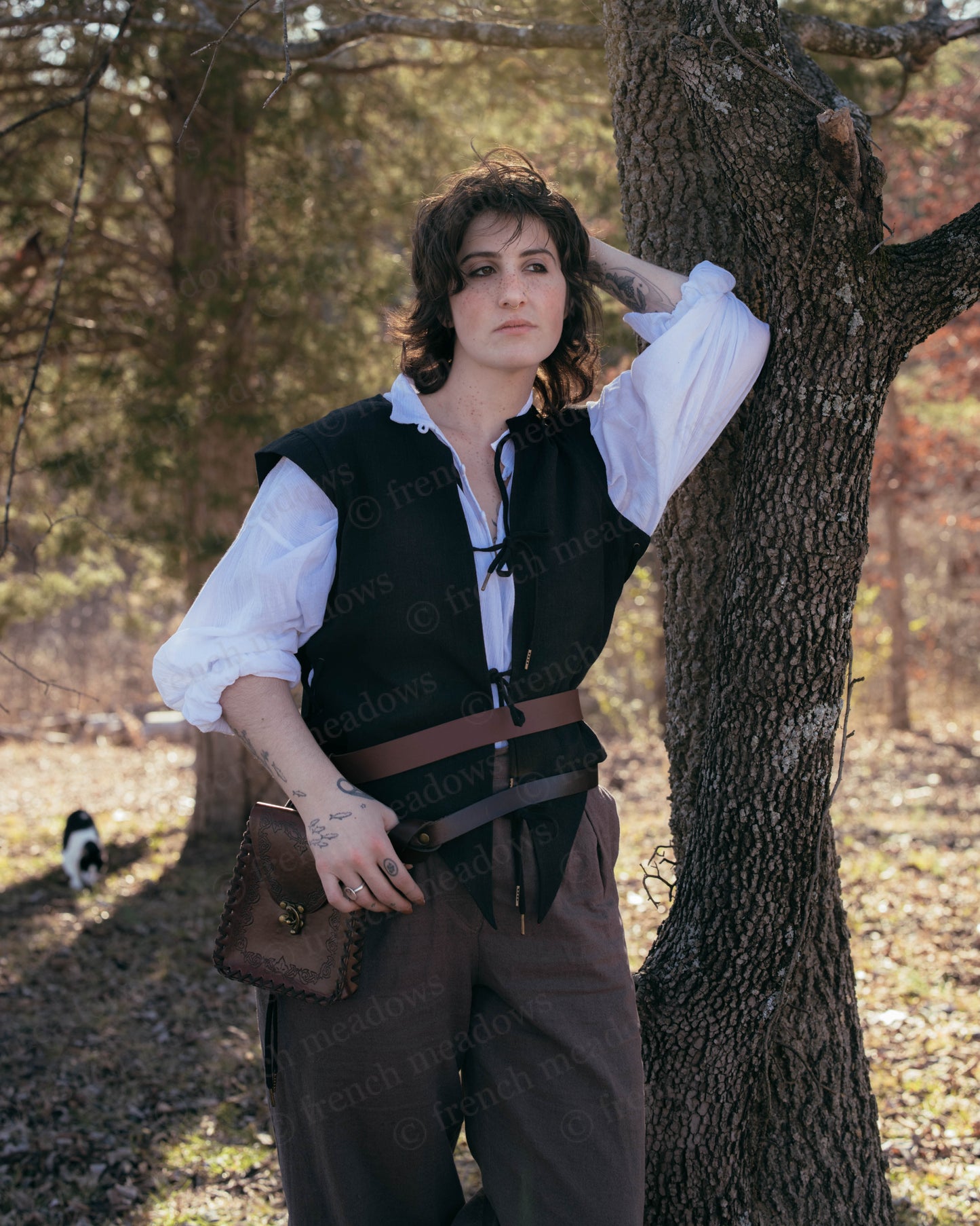 Black Bard Vest shown with white peasant shirt and brown trousers in outdoor Renaissance costume setting against autumn tree