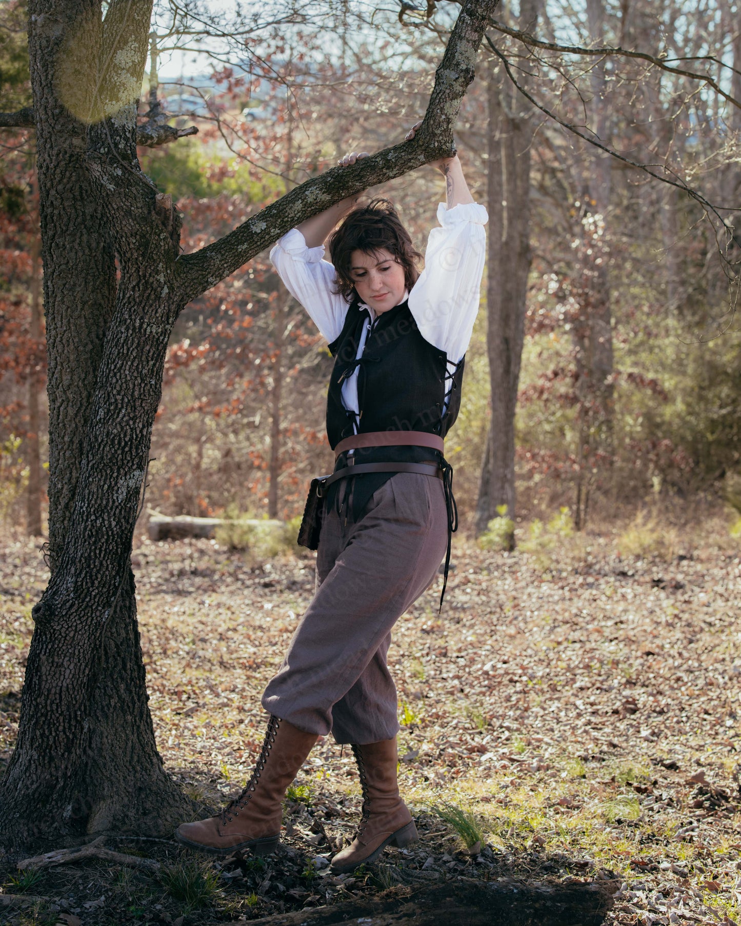Black Bard Vest shown in woodland setting with white shirt, brown pants and boots, displaying renaissance style costume detail