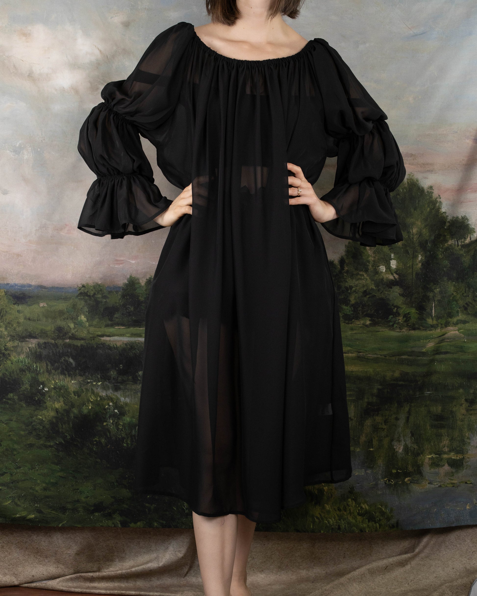 Black Chiffon Long Sleeve Chemise with flowing ruffled sleeves and elastic neckline, shown against pastoral landscape backdrop