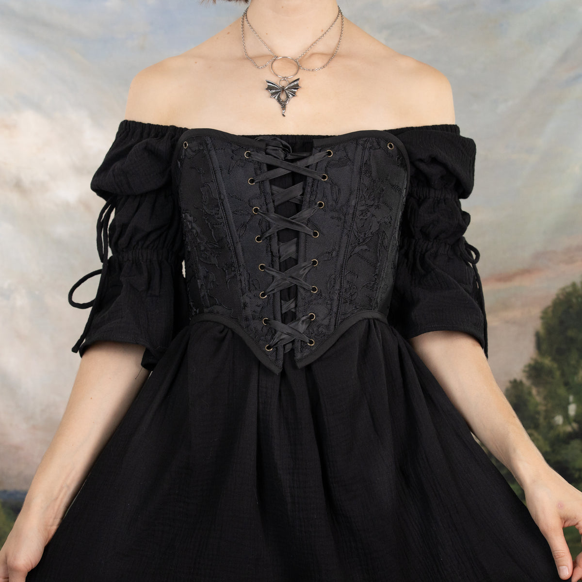 model wearing a strapless black corset, the straps have been removed to show two different options of wearing the corset with or without straps