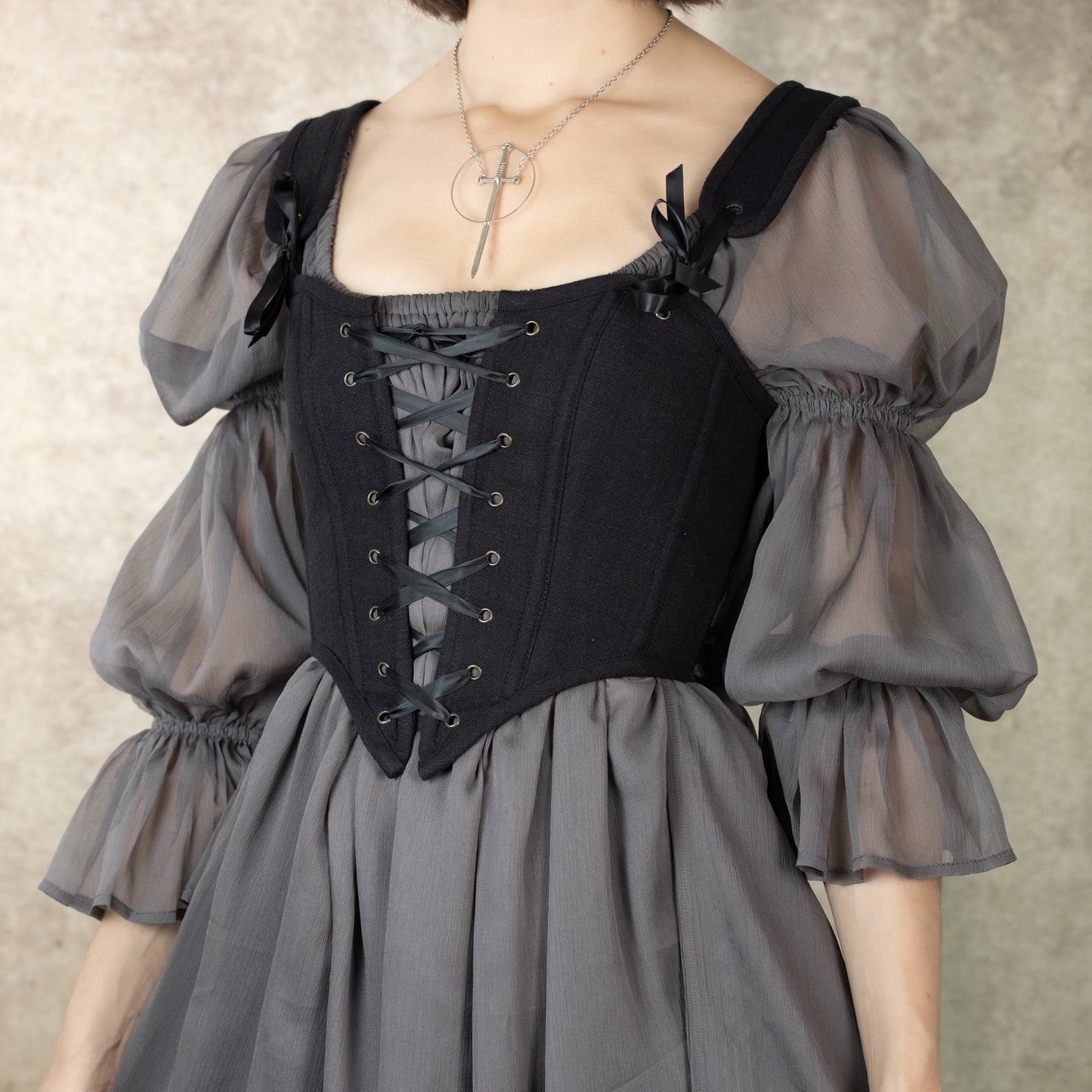 Black cotton corset top with puff sleeve gray dress featuring front lace-up design and square neckline, styled as vintage inspired