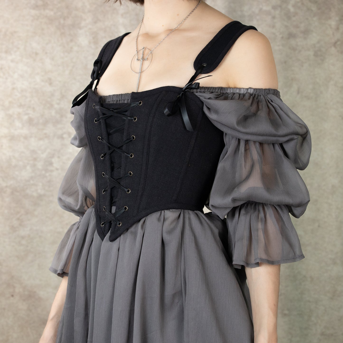 Black cotton corset top with adjustable straps and front lacing, paired with flowing gray puffy sleeves and midi dress