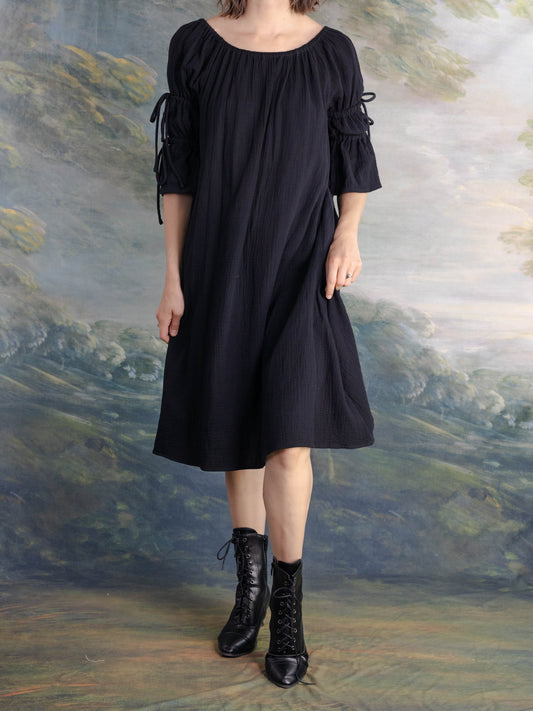 Woman wearing a Black Cotton Puff Sleeve Chemise with mid-length sleeves and a flowing silhouette against a painted backdrop