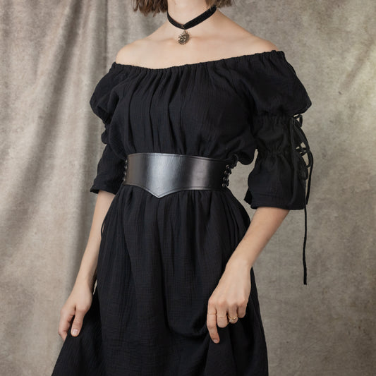 Wide leather waist belt shown on black off-shoulder dress, featuring medieval-style design with side lacing and carved details