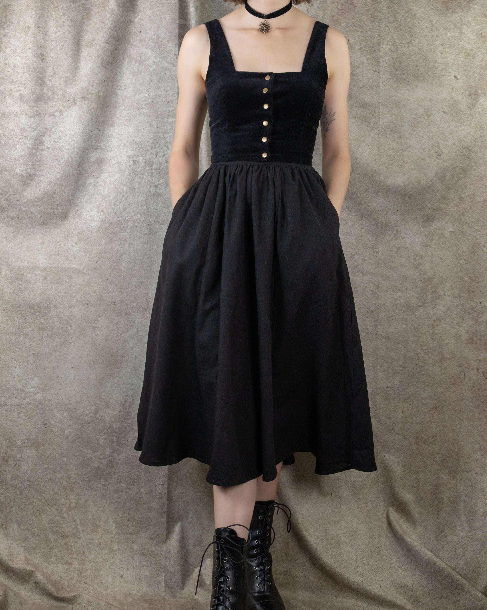 Black Cotton Midi Skirt shown on model, featuring button-front bodice, full gathered skirt, and side pockets against grey backdrop