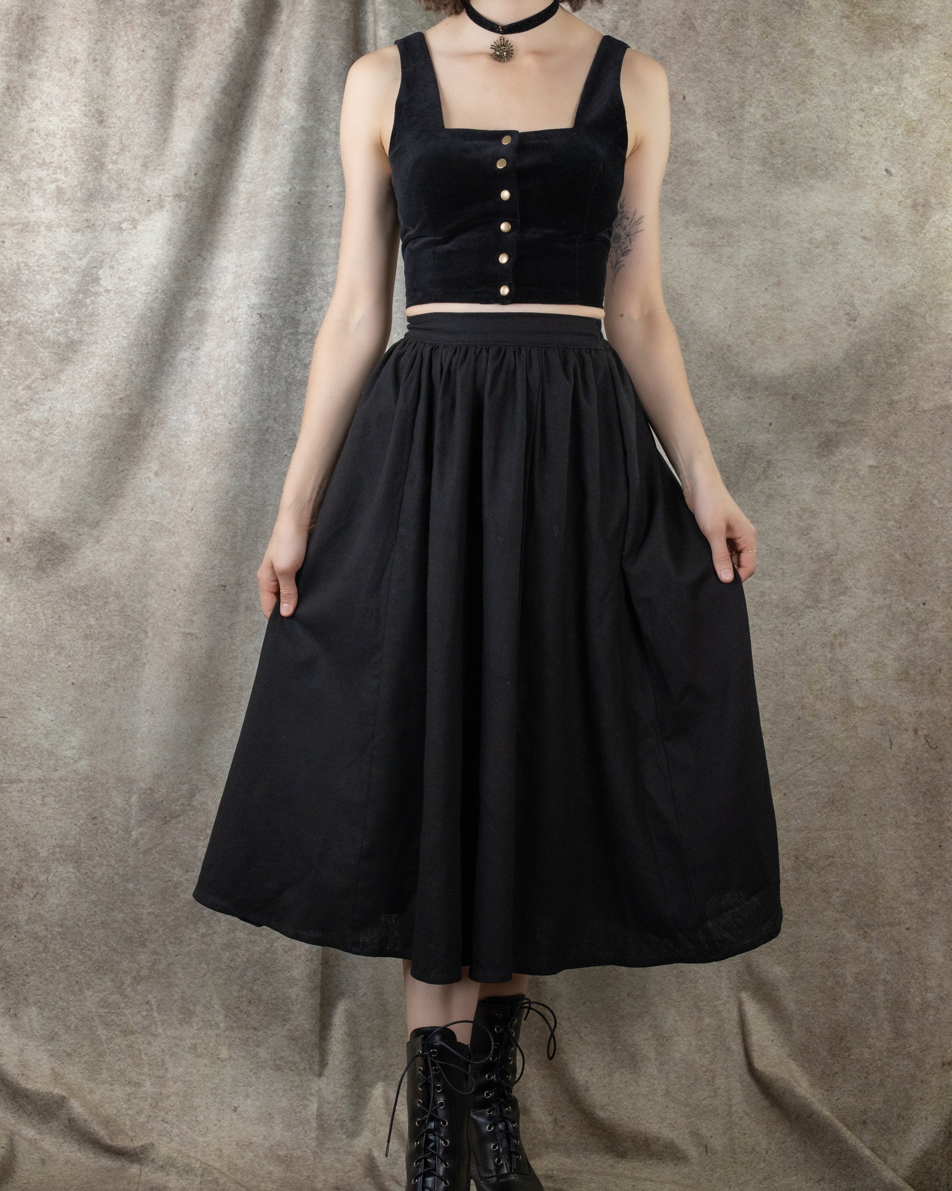 Black Cotton Midi Skirt shown in full-length view, paired with velvet crop top and boots, displaying flowing A-line silhouette