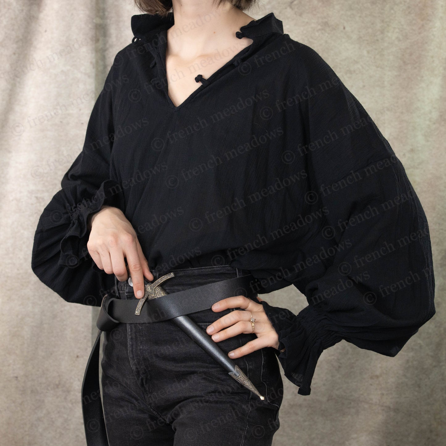 Darcy Shirt in black cotton with billowing poet sleeves and knotted button closure, styled with leather belt