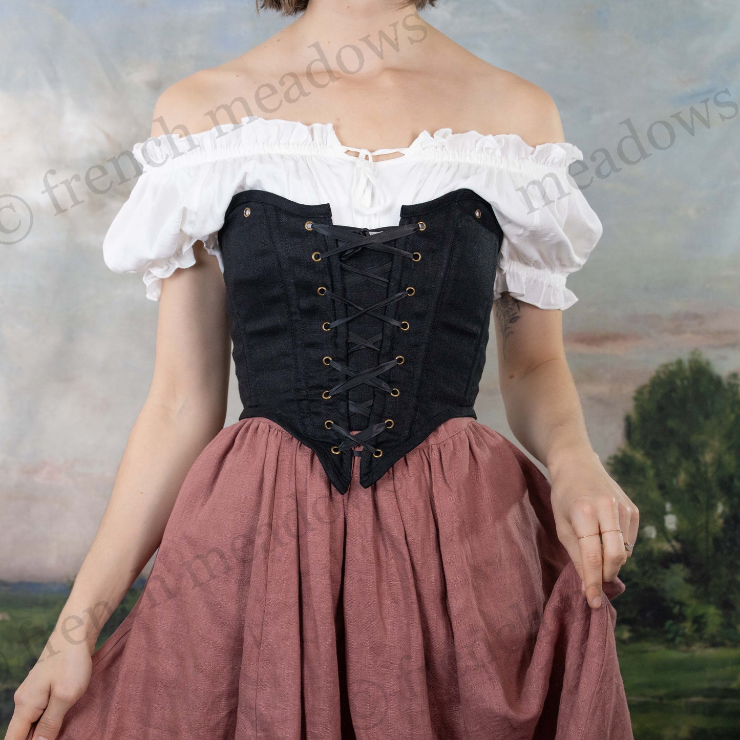 Black cotton corset top with off-shoulder white peasant blouse, lace-up front detail and mauve skirt in historical costume style