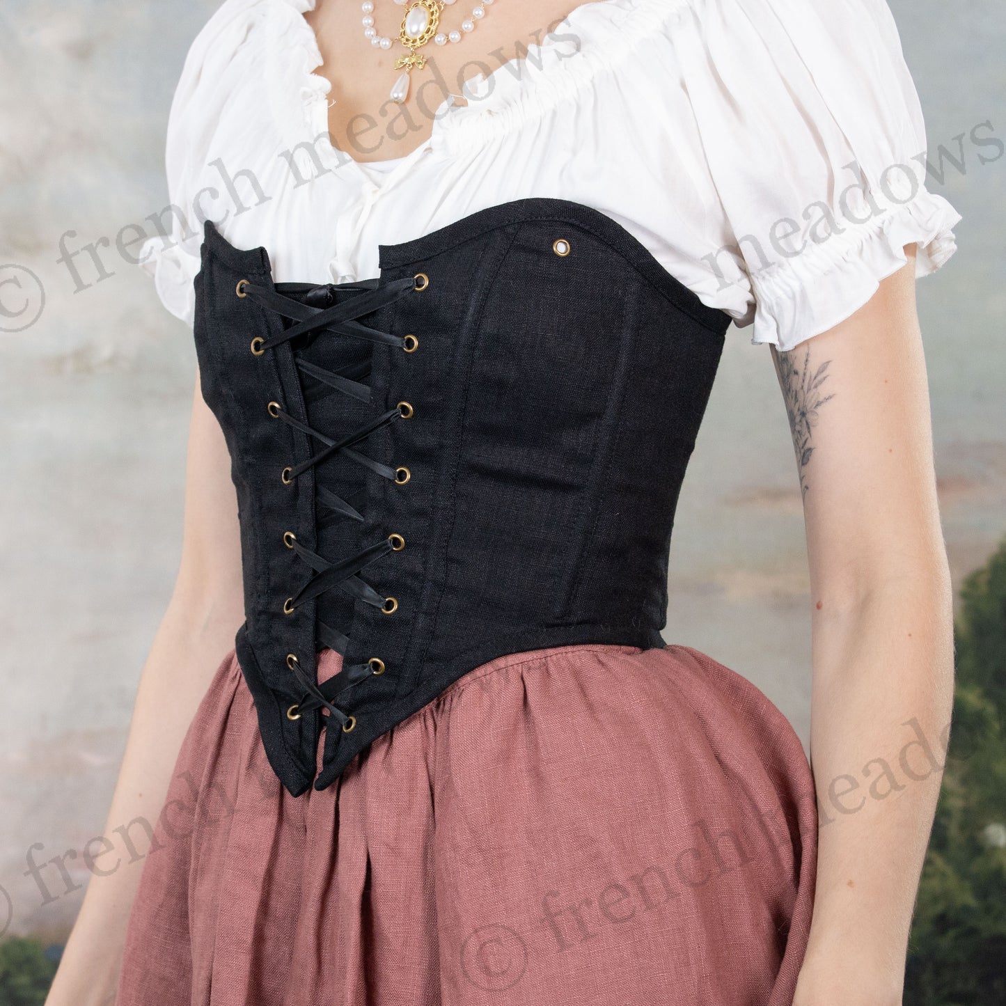 Black cotton corset top with front lacing worn with white peasant blouse and dusty rose skirt in historical costume style