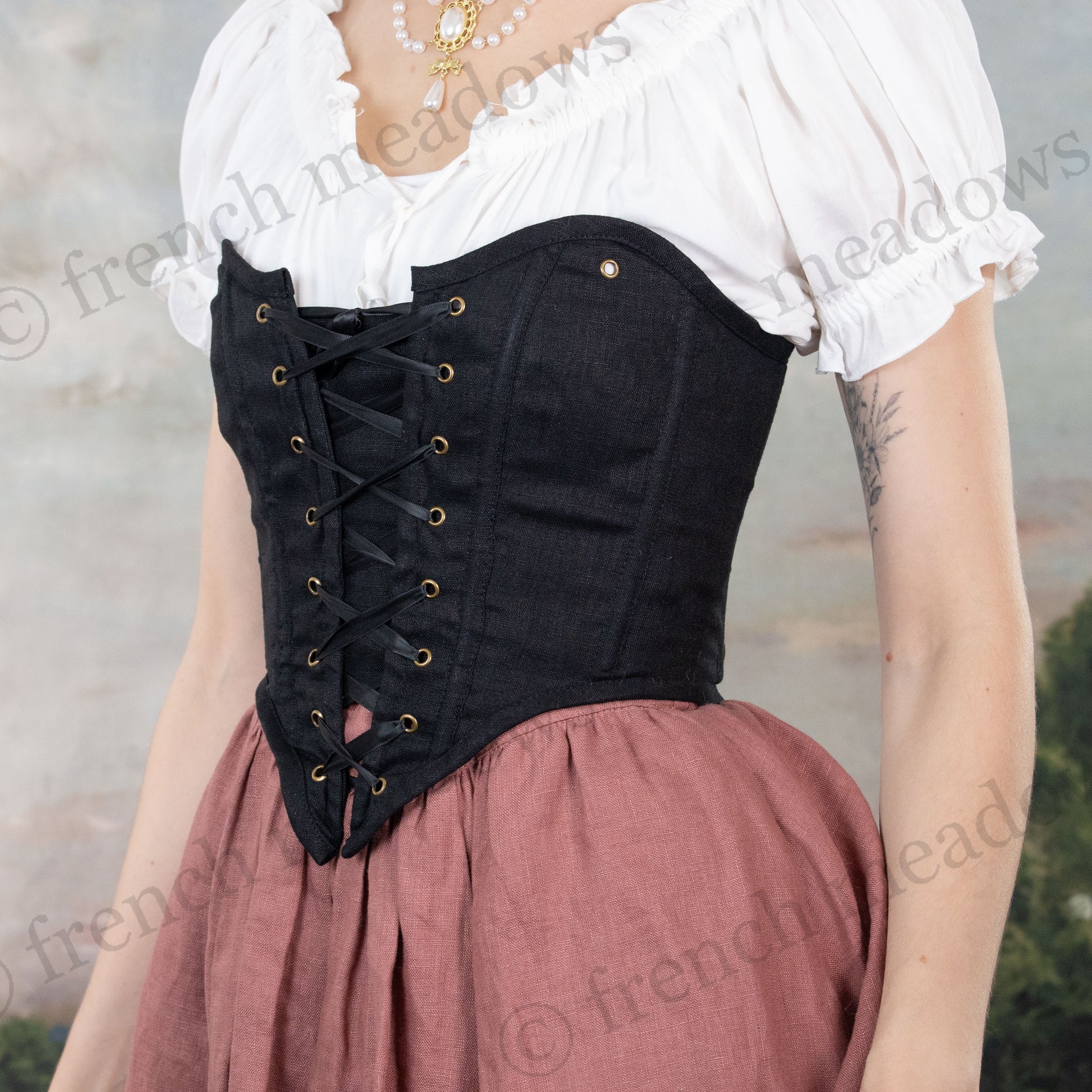 Black cotton corset top with front lacing worn with white peasant blouse and dusty rose skirt in historical costume style