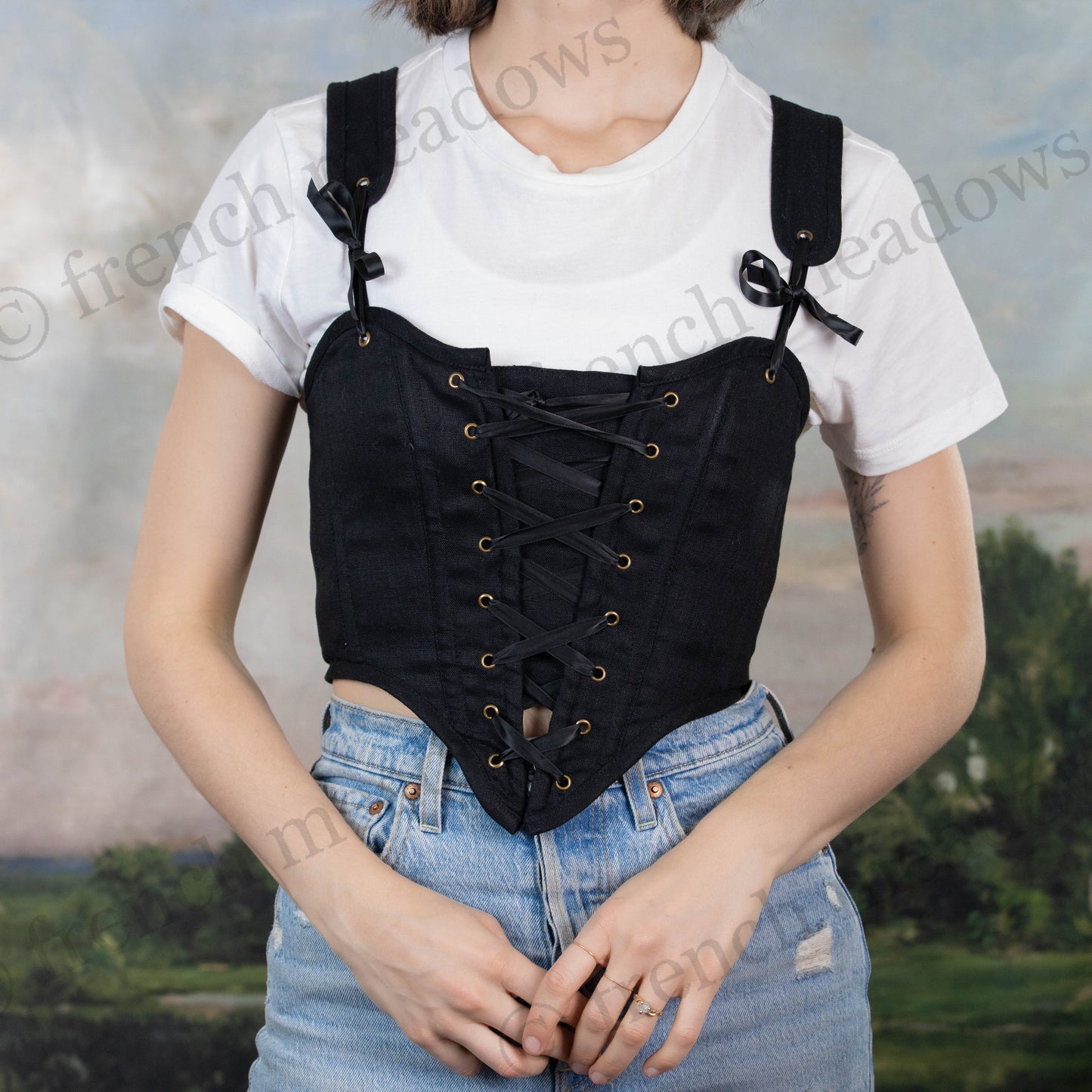 Black cotton corset top worn over white t-shirt with lace-up front detail and adjustable shoulder straps