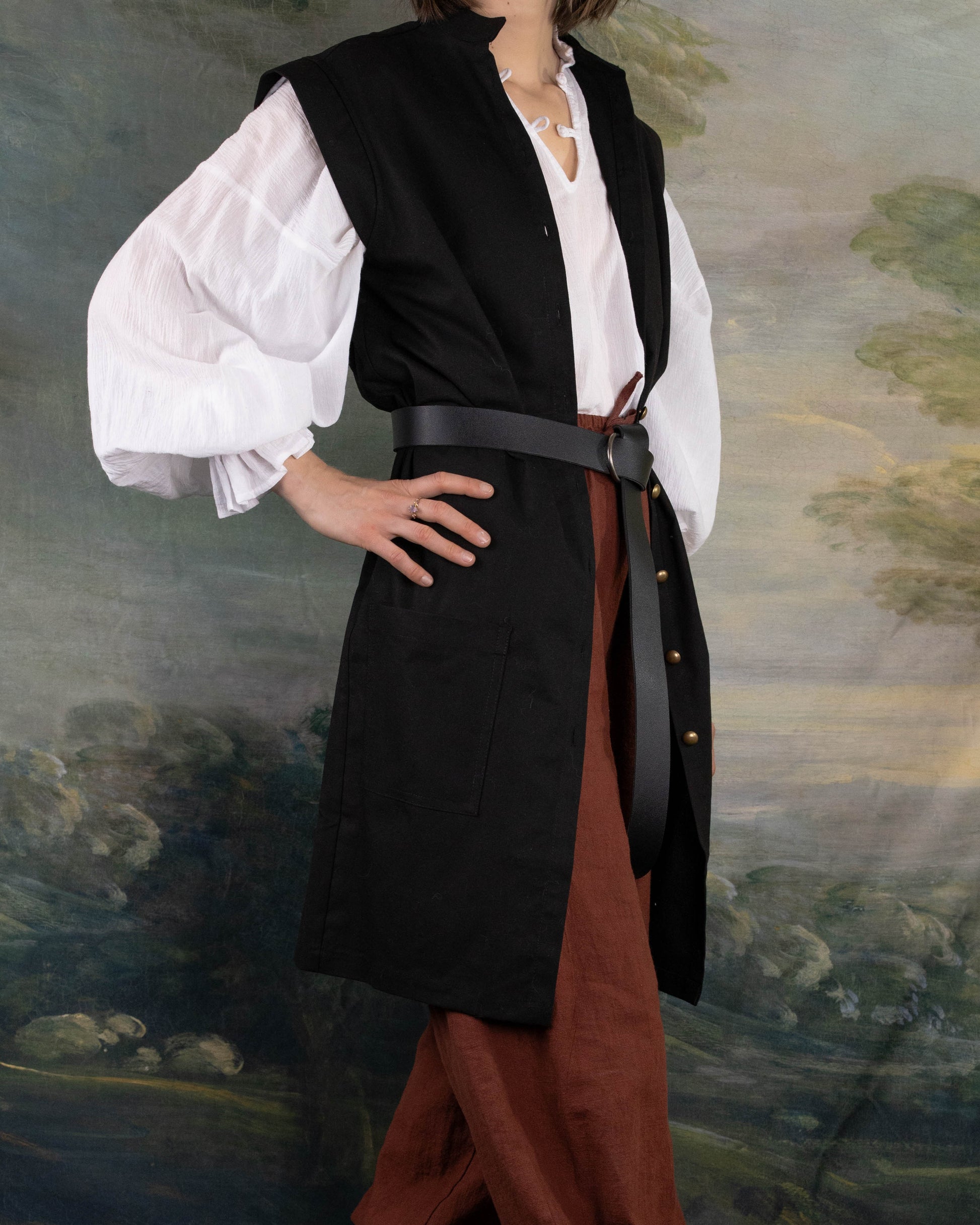 Black Pirate Vest shown over white shirt with wide leather belt and brown pants in renaissance style.