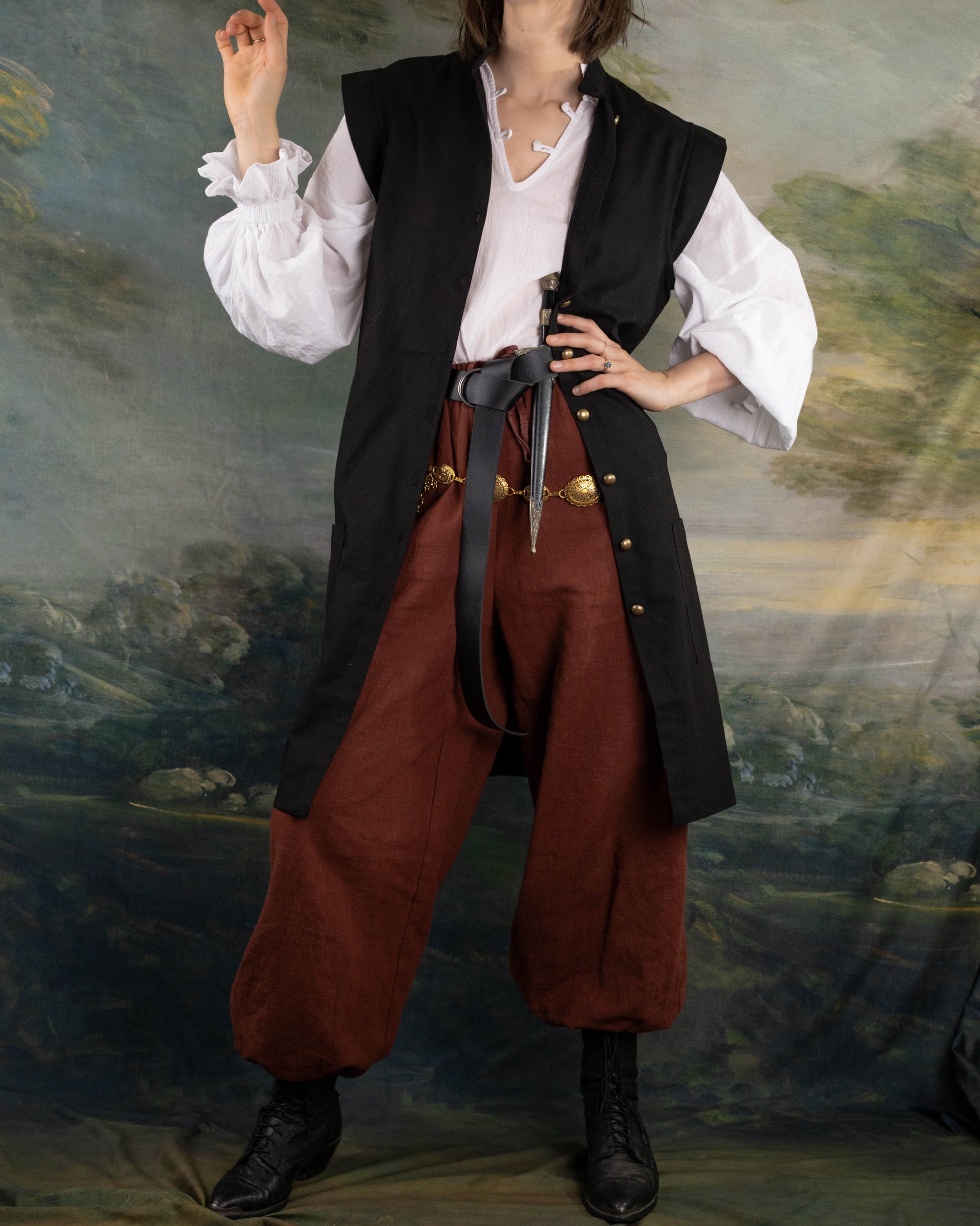 Black Pirate Vest worn over white shirt and brown pants with black boots in renaissance costume setting.