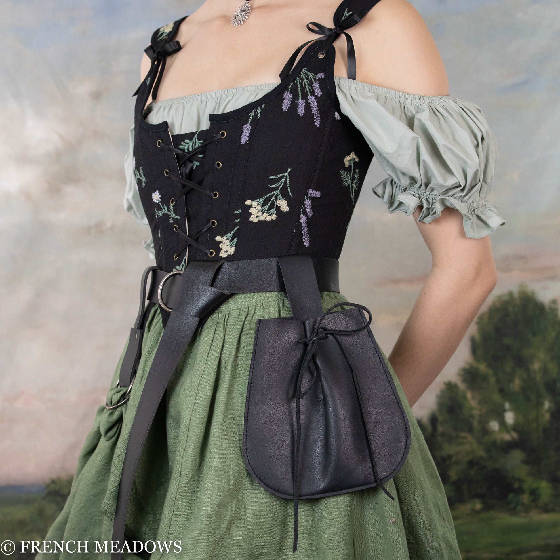 Black drawstring pouch attached to belt with medieval dress, floral corset and green skirt in outdoor setting