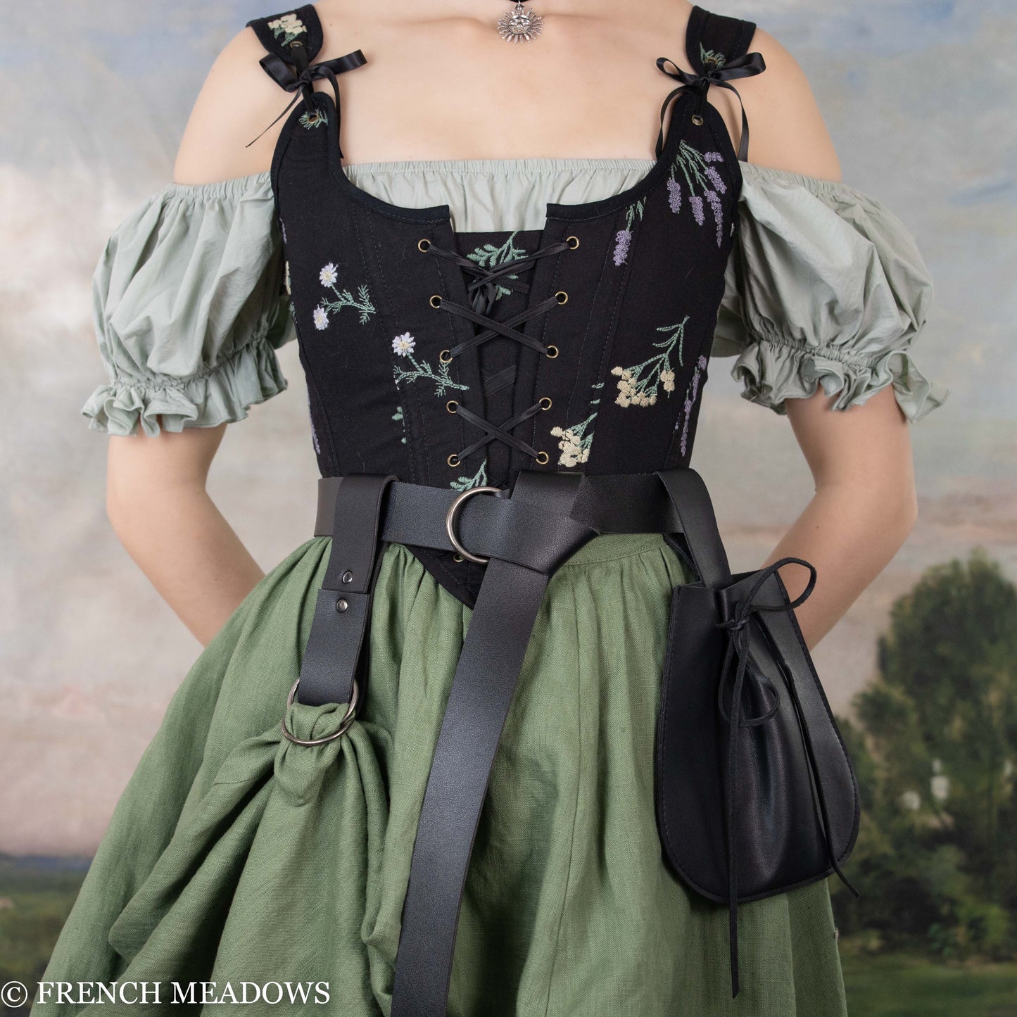 Black vegan leather skirt hikes shown on renaissance dress with floral corset and green skirt