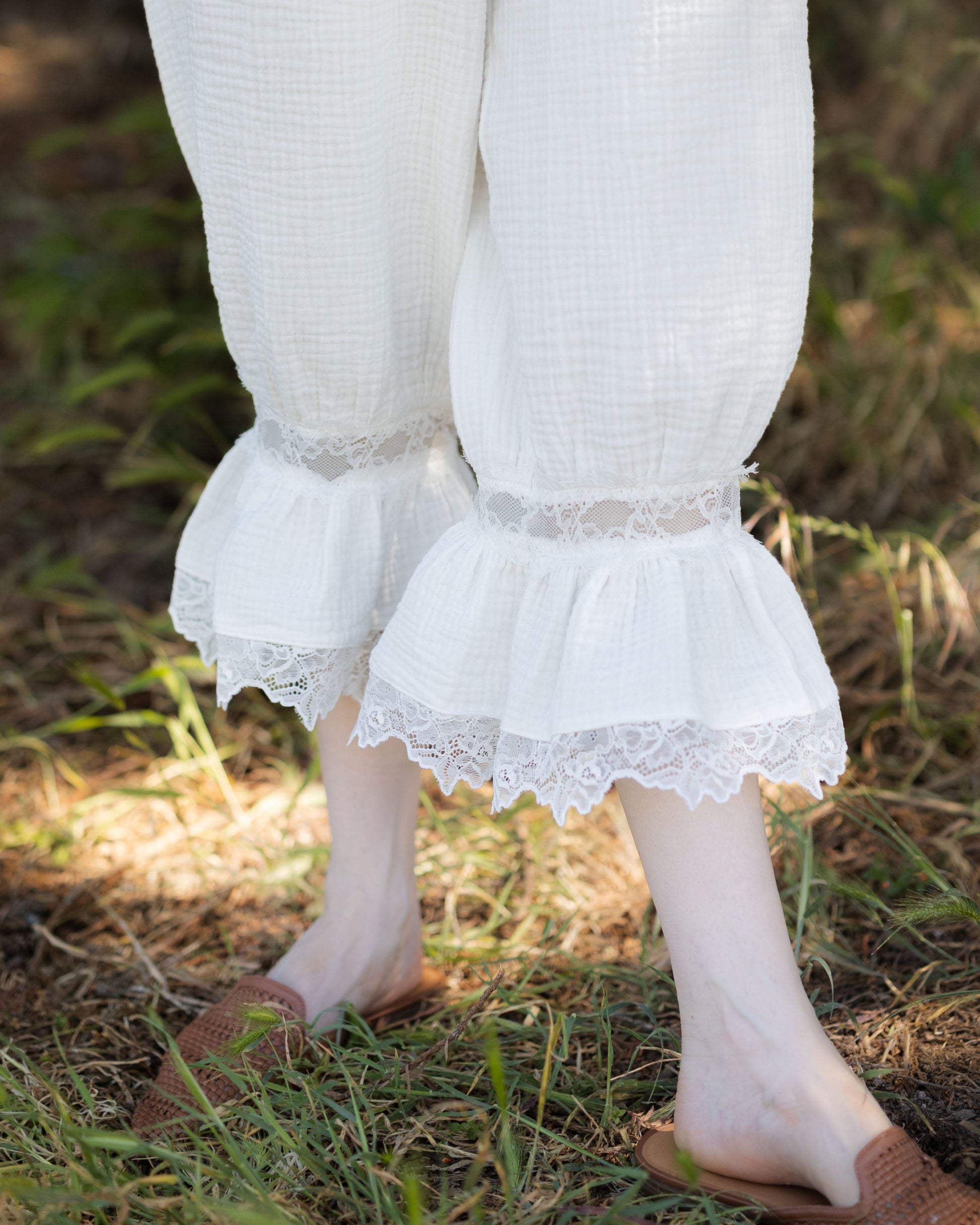 White cotton bloomer pantaloons with lace ruffle hems on legs, worn outdoors with brown slip-on shoes.