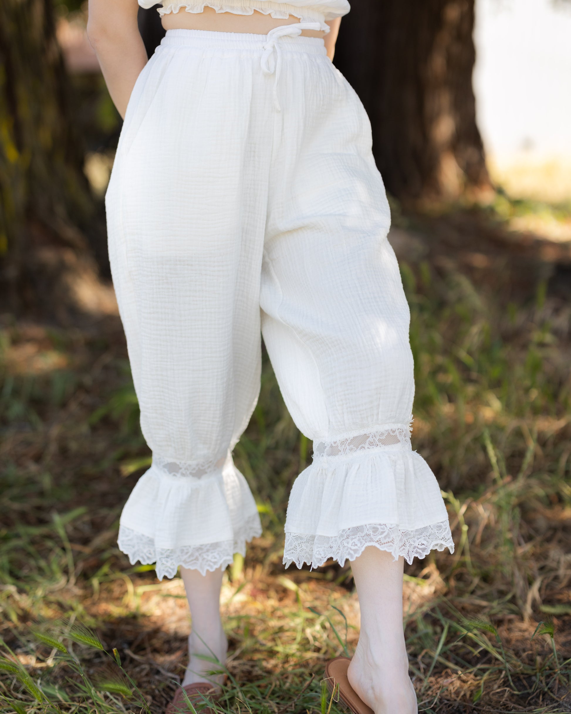 White cotton bloomer pantaloons with lace ruffle hem, adjustable waist, and lightweight breathable fabric.