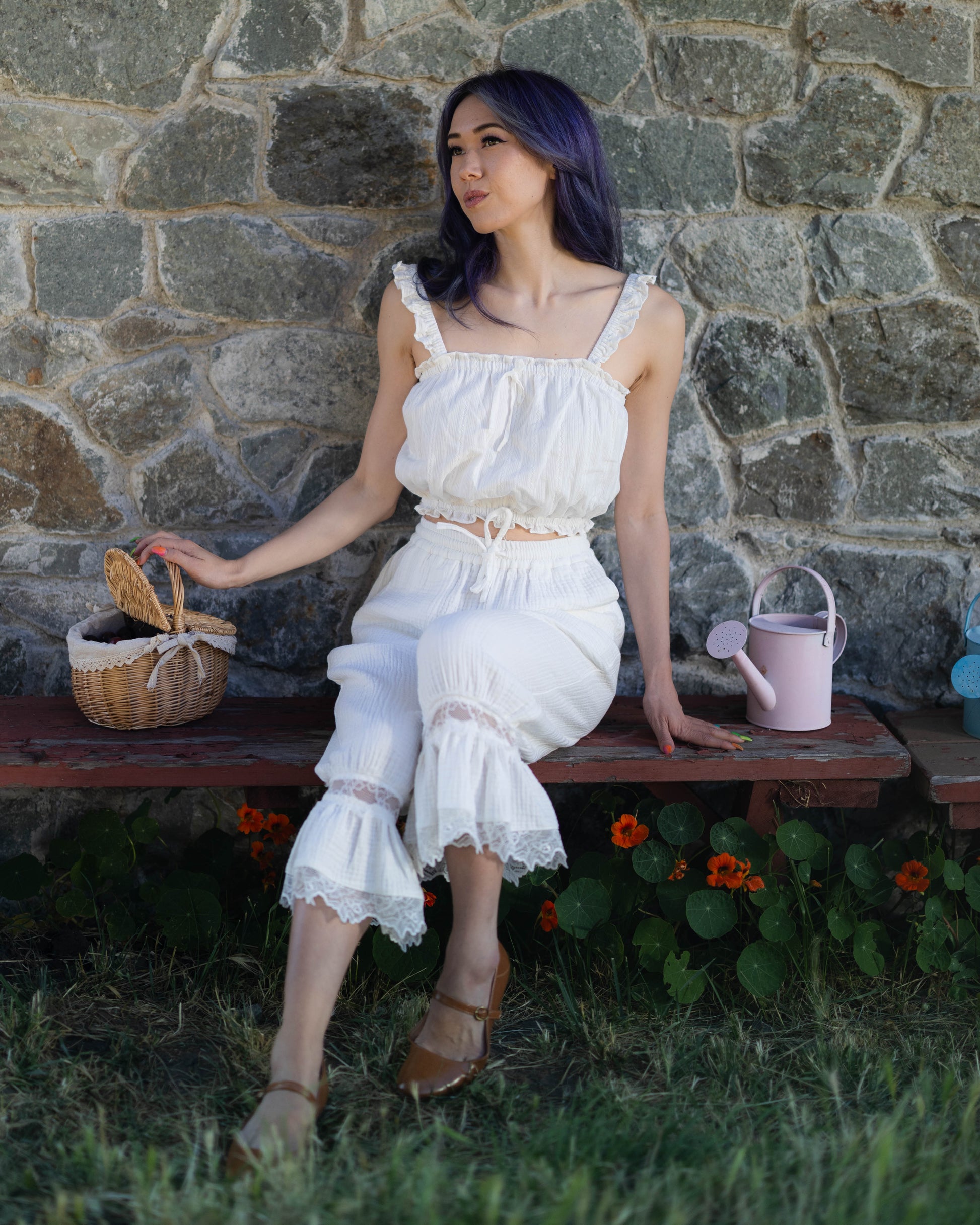 Woman wearing white cotton bloomer pantaloons with lace ruffle hem sitting on a bench outdoors