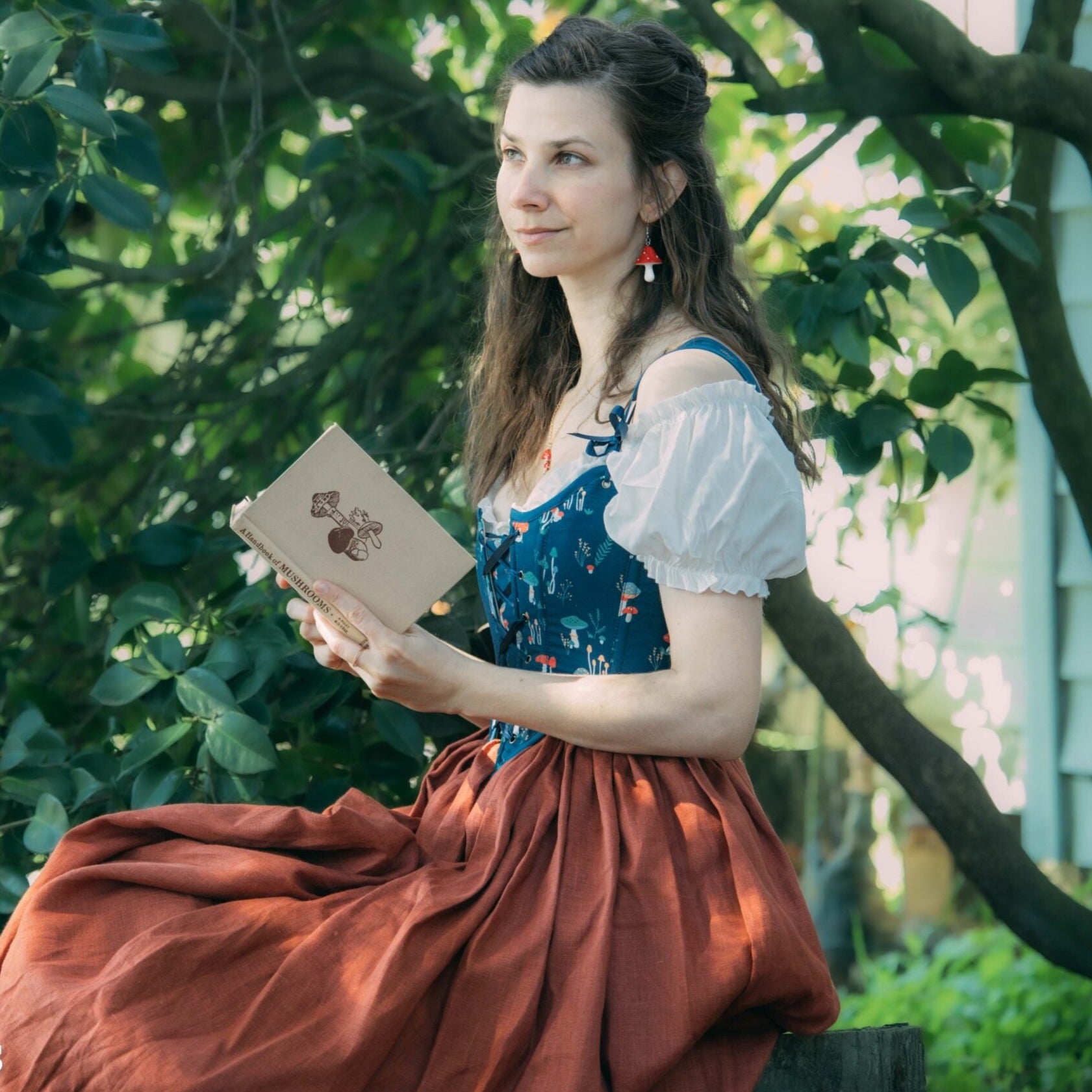 Blue Mushroom Renaissance Bodice shown in outdoor setting with red skirt, white blouse and nature-inspired mushroom detailing