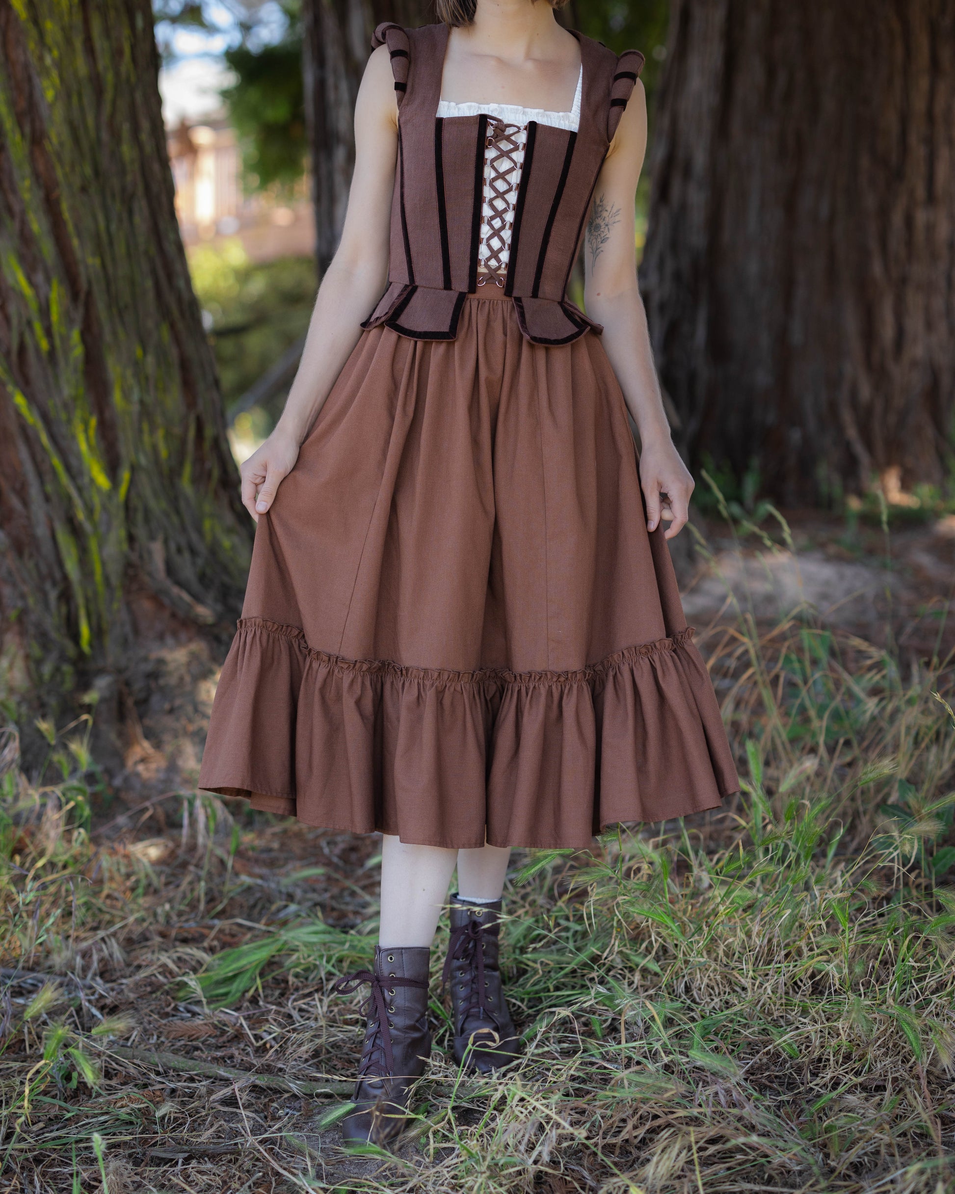 Woman wearing a brown linen ruffle skirt paired with a corset top in an outdoor forest setting