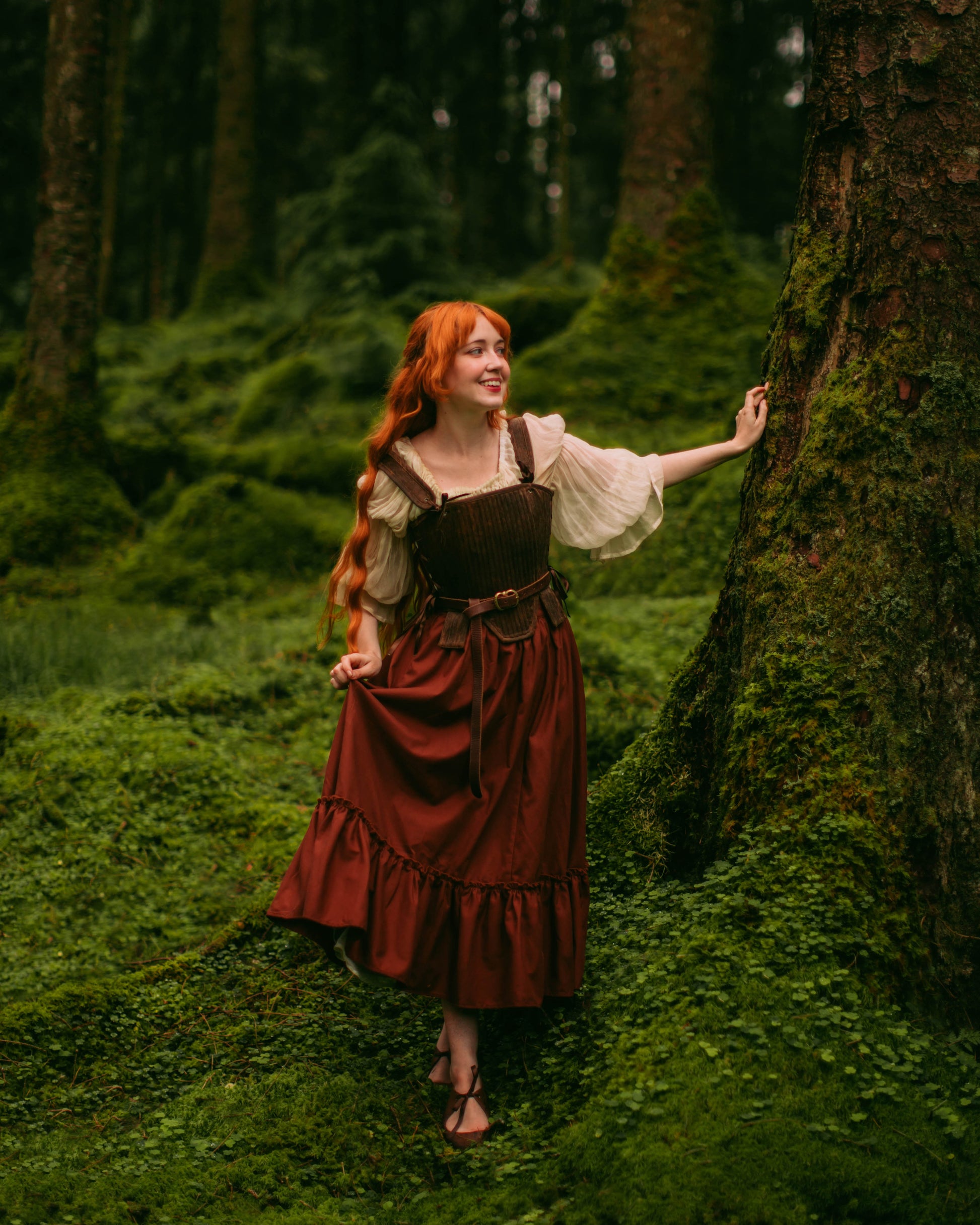 Woman wearing a rust linen midi skirt with elastic waistband in a green mossy forest setting