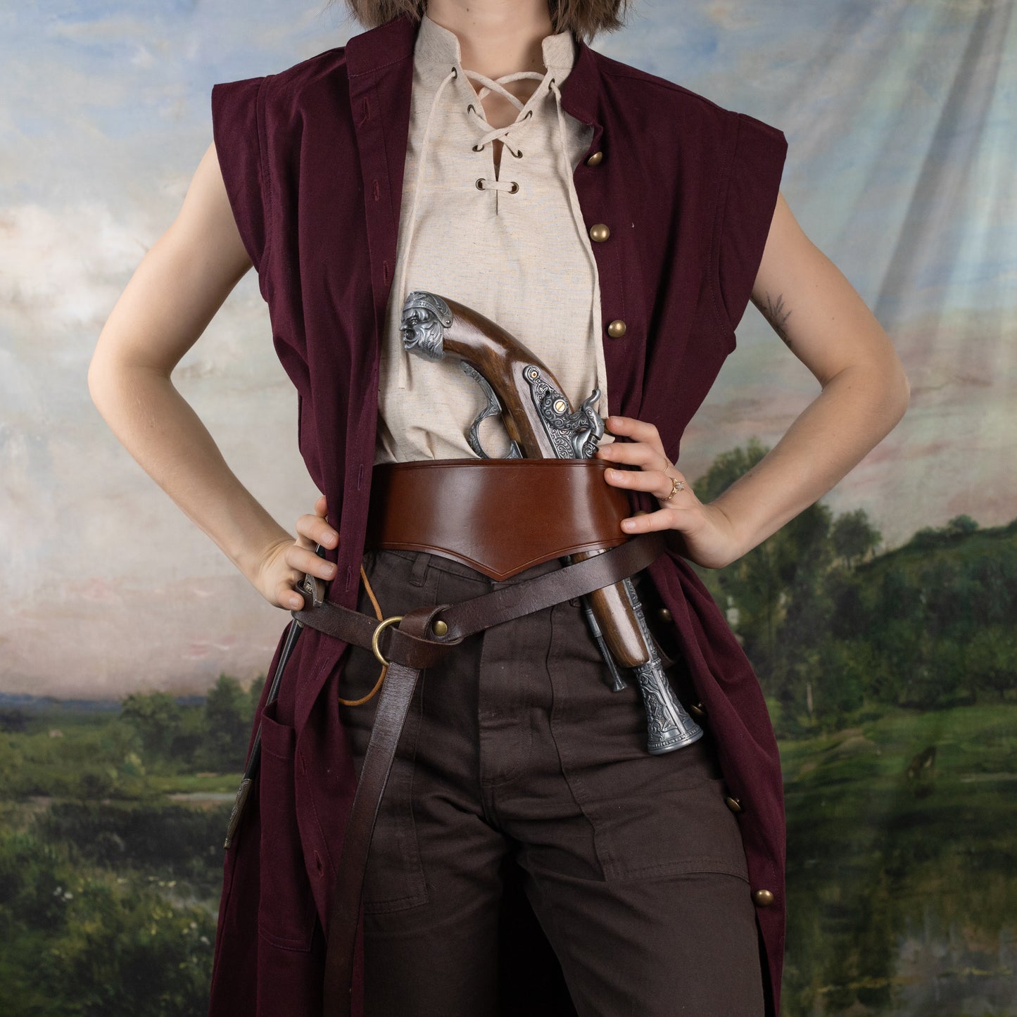 Burgundy Pirate Vest worn over a beige lace-up shirt with wide leather belt and antique pistol accessory.
