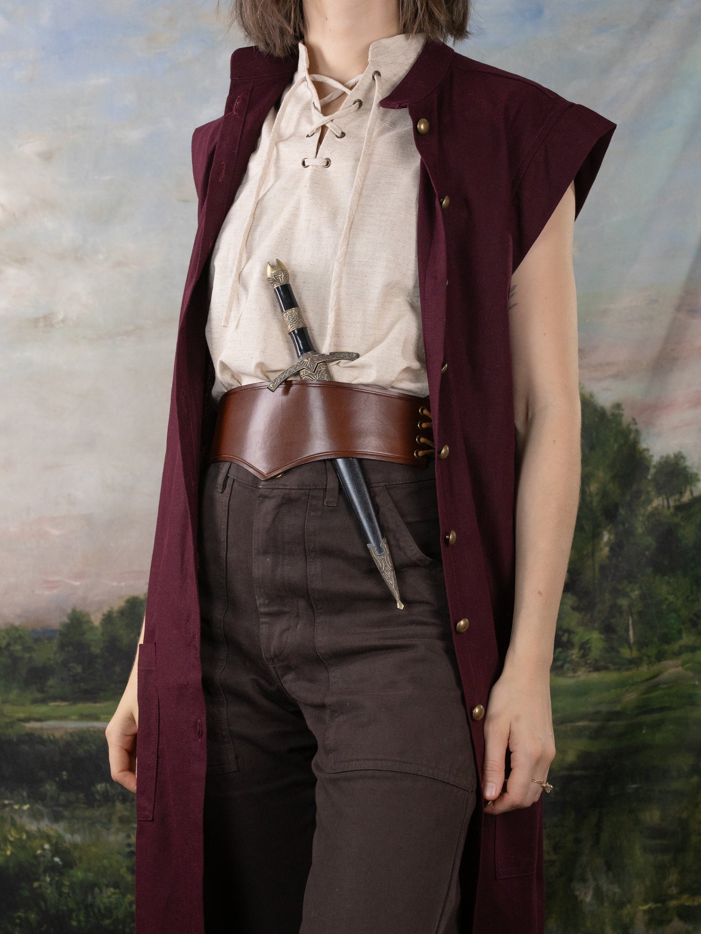 Burgundy Pirate Vest made of rich linen, styled over a lace-up shirt with a leather belt and dagger for a historical look.