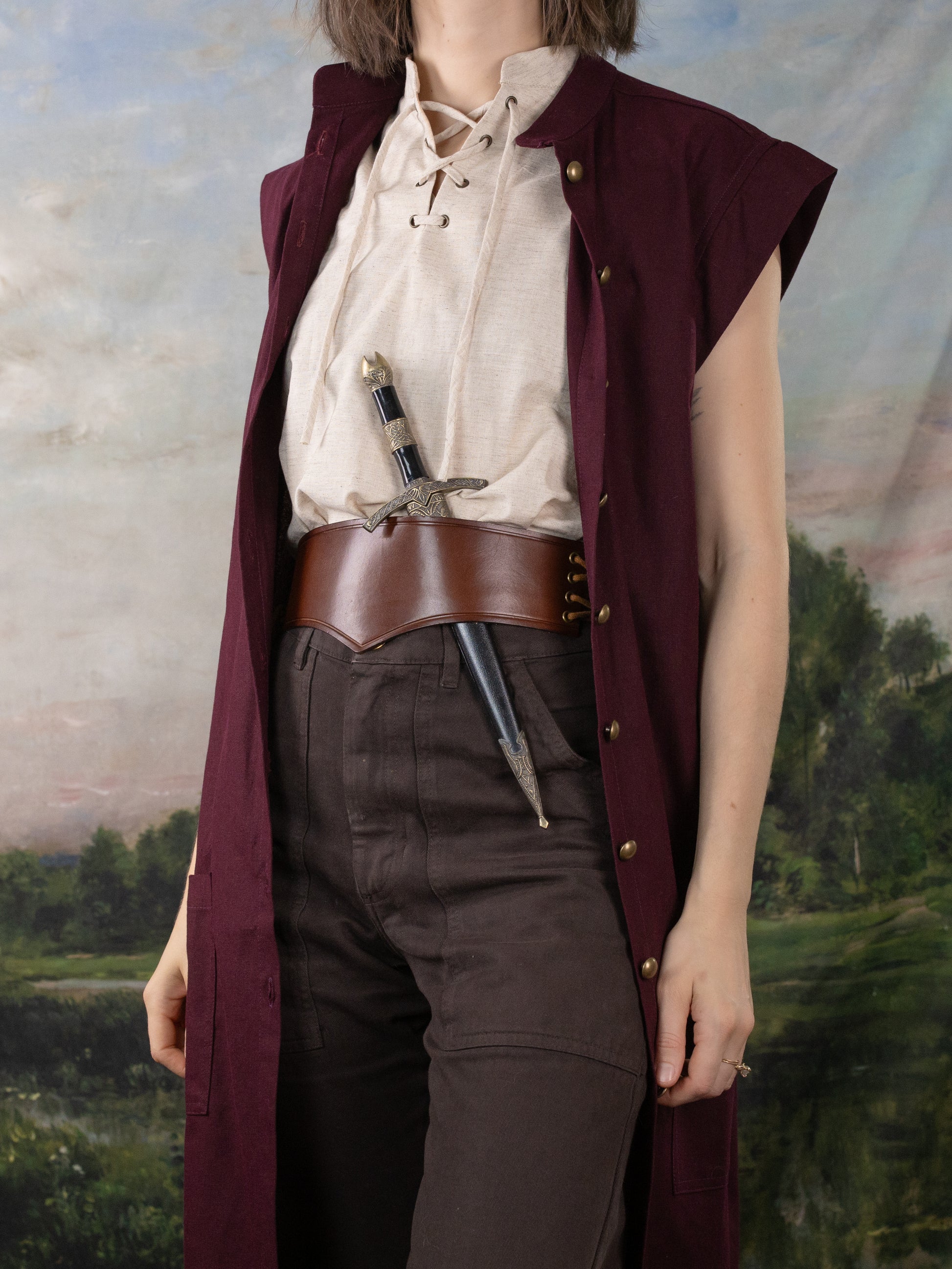 Burgundy Pirate Vest made of rich linen, styled over a lace-up shirt with a leather belt and dagger for a historical look.