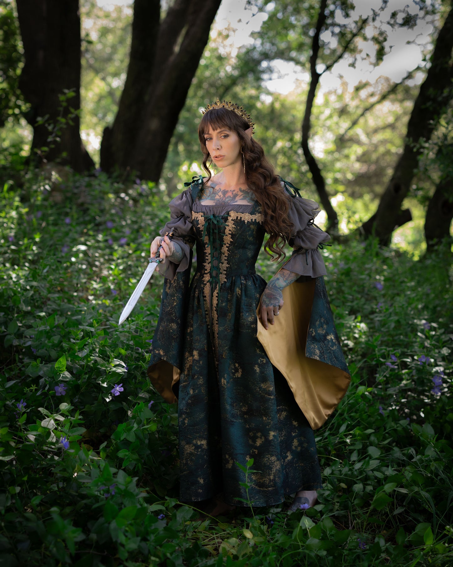 Dark Green Jacquard Corset Dress with gold trim, adjustable lacing, and removable bell sleeves in a forest setting.