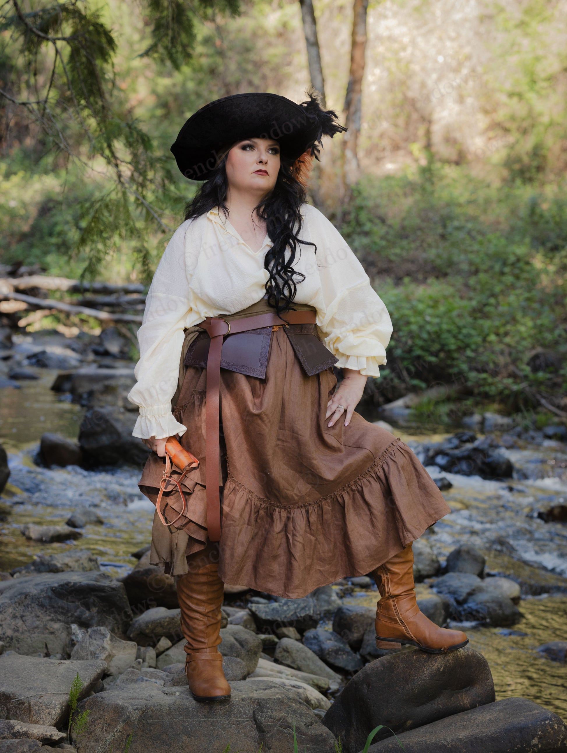 Debossed leather underbust corset shown in medieval costume style with brown skirt and white blouse in outdoor creek setting