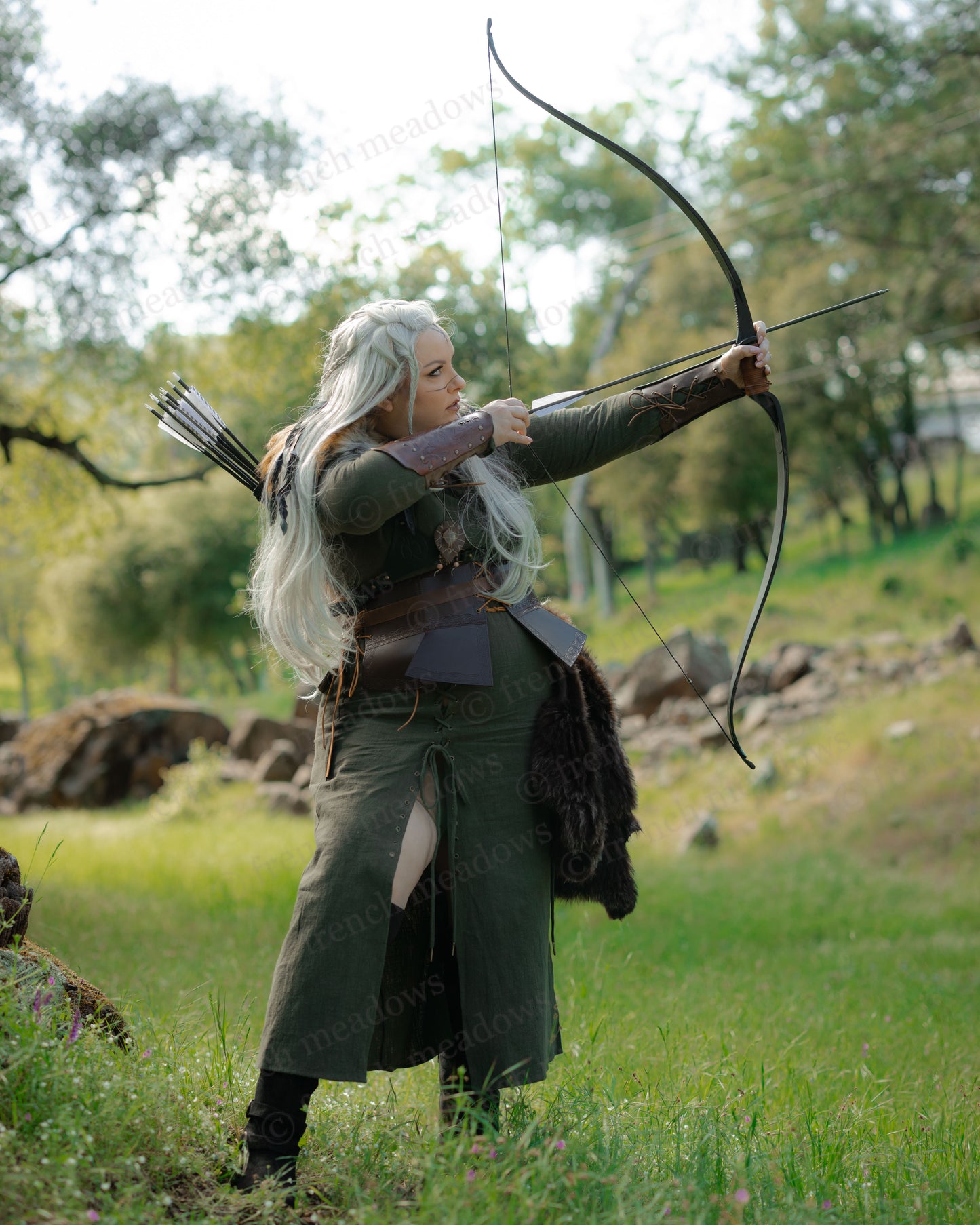 Olive Green Viking Dress worn by archer in woodland, featuring front lacing slit and rustic textured fabric.