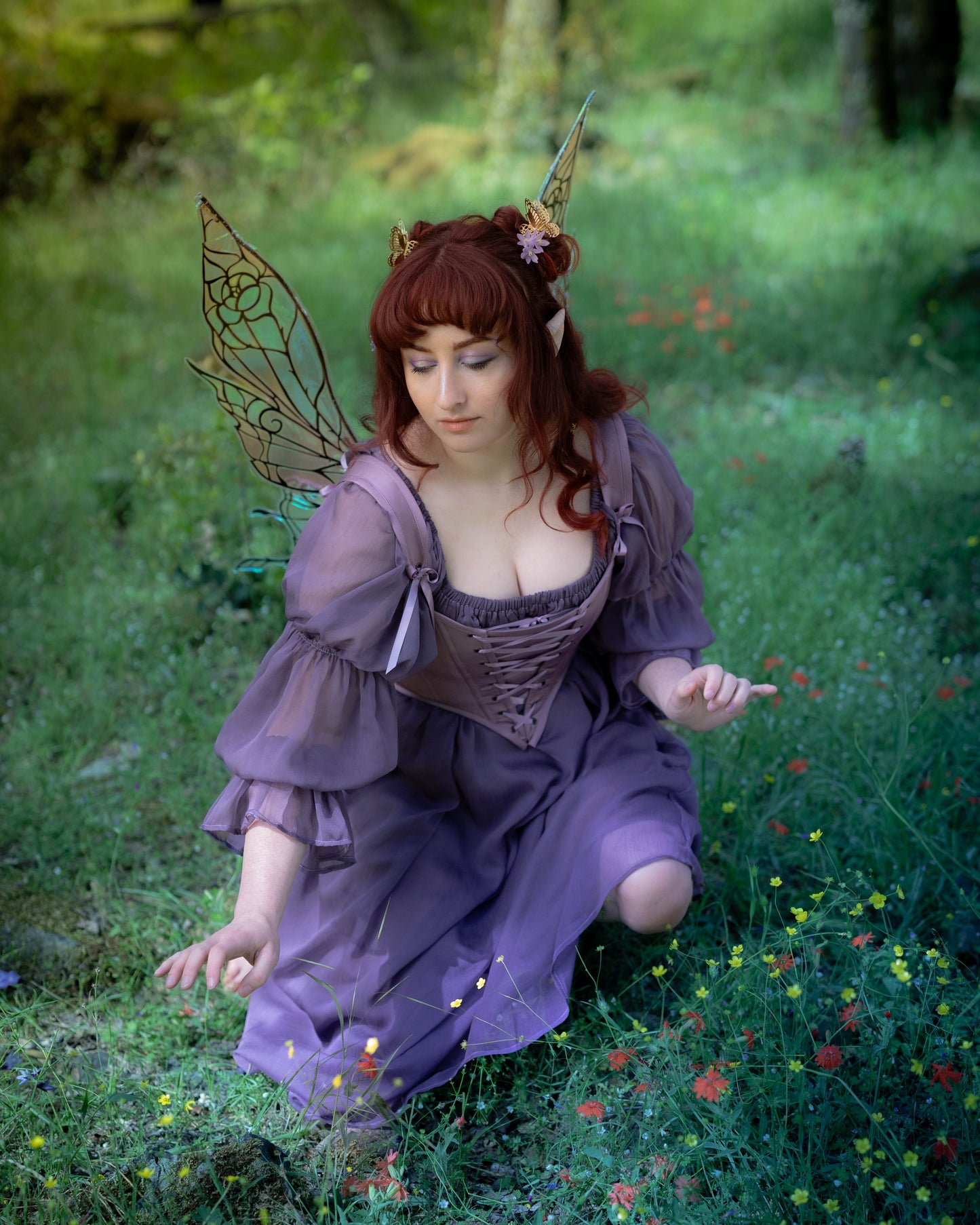 Woman wearing a Purple Dusk Satin Corset Top in a forest, embodying dark fairy allure with delicate wings and floral accents.