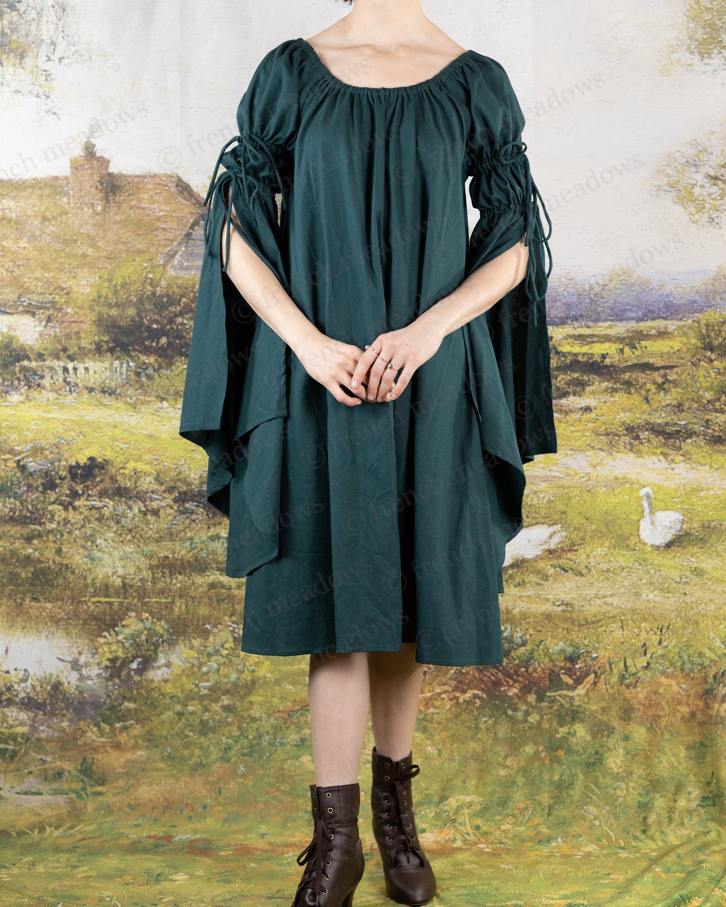Dark Green Linen Bell Sleeve Chemise dress with flowing medieval-style sleeves and elastic neckline shown against pastoral backdrop