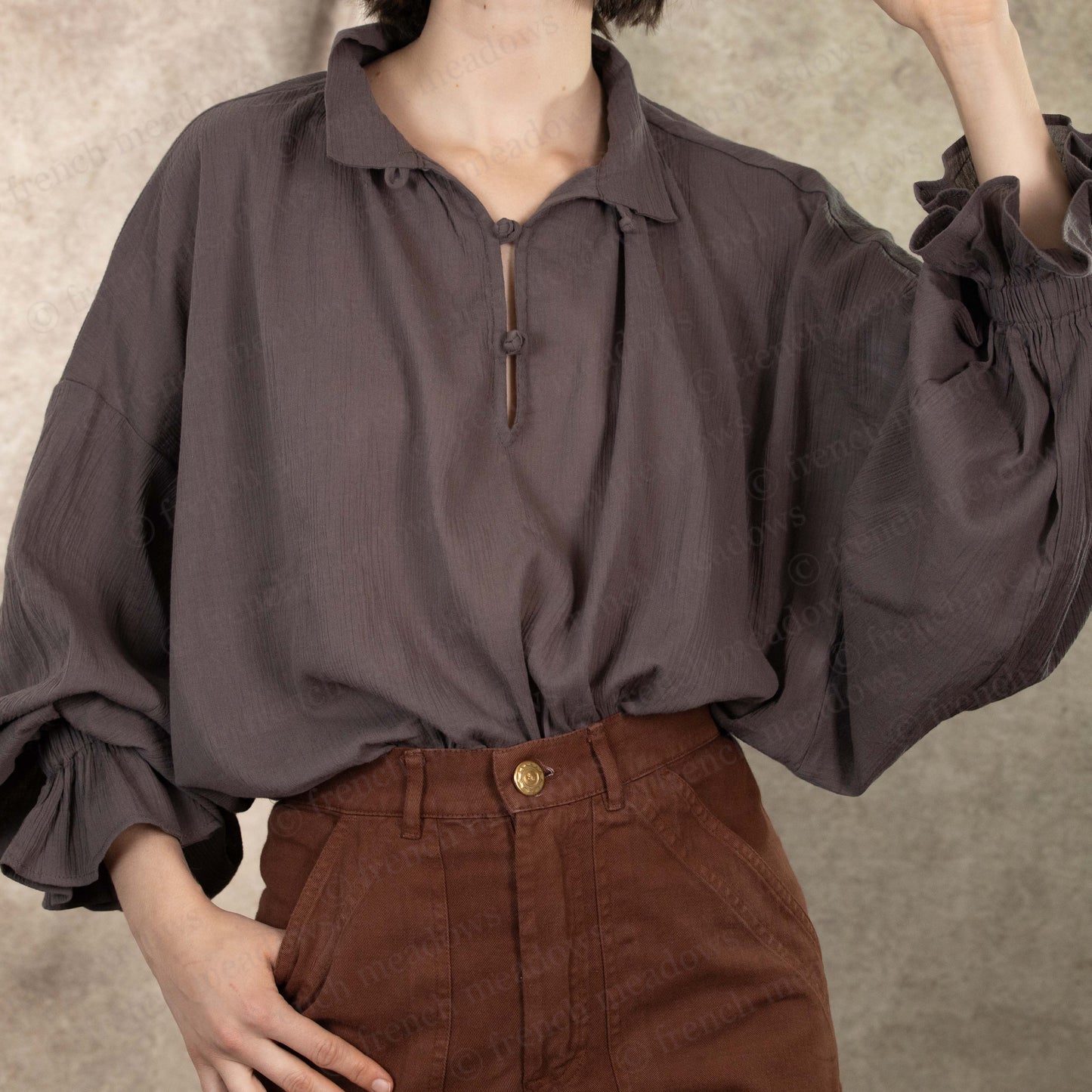 Darcy Shirt in charcoal gray cotton with billowing poet sleeves and vintage-style button closure, paired with brown pants