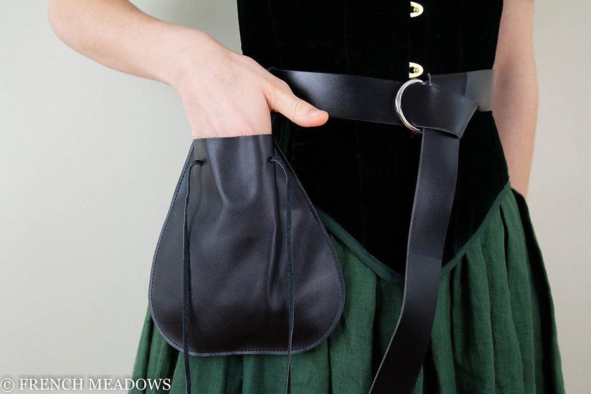 Black drawstring pouch attached to leather belt, shown against green skirt and black velvet top in medieval costume style