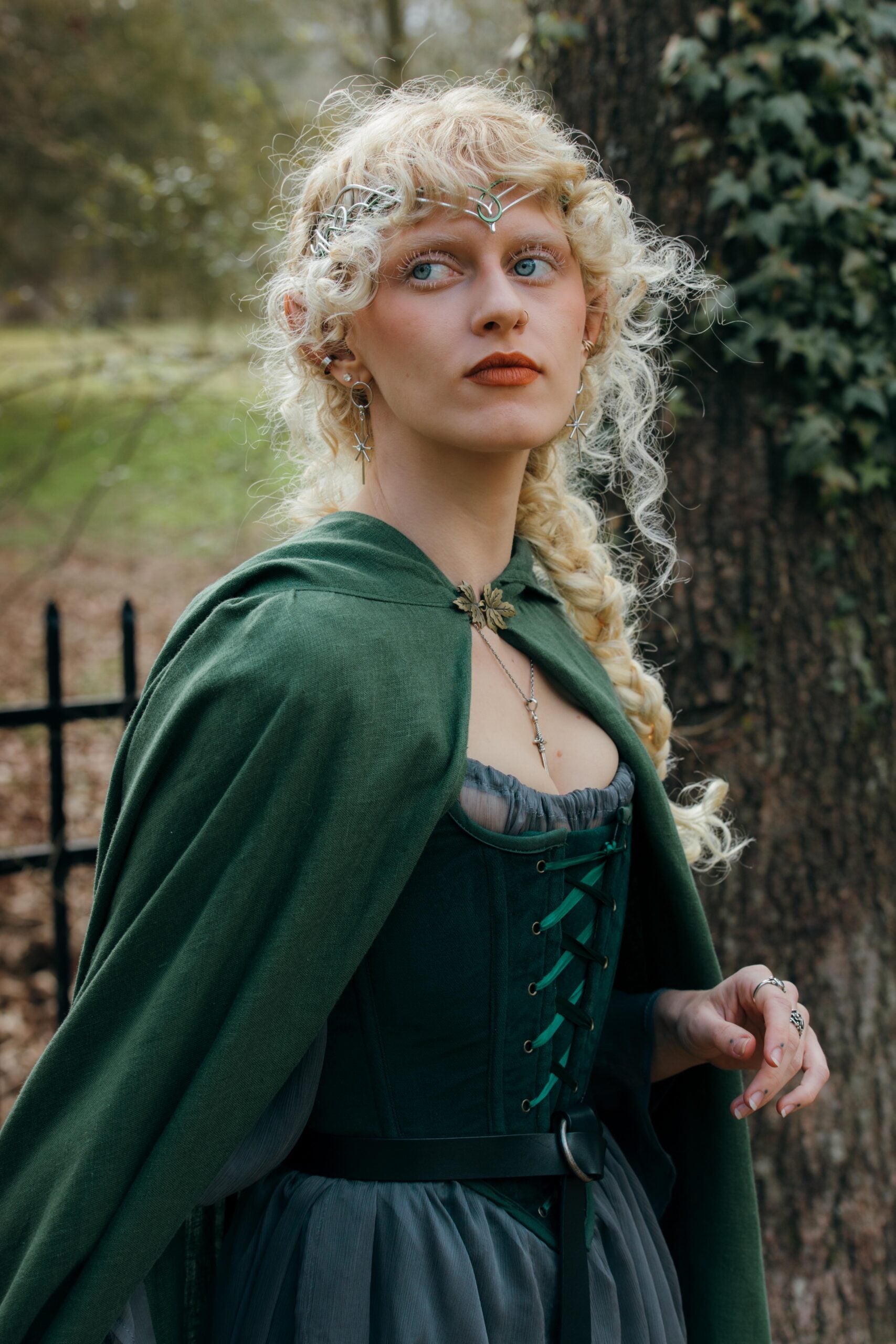 Linen Renaissance Cloak in forest green worn over period dress, photographed in a woodland setting with ivy-covered trees